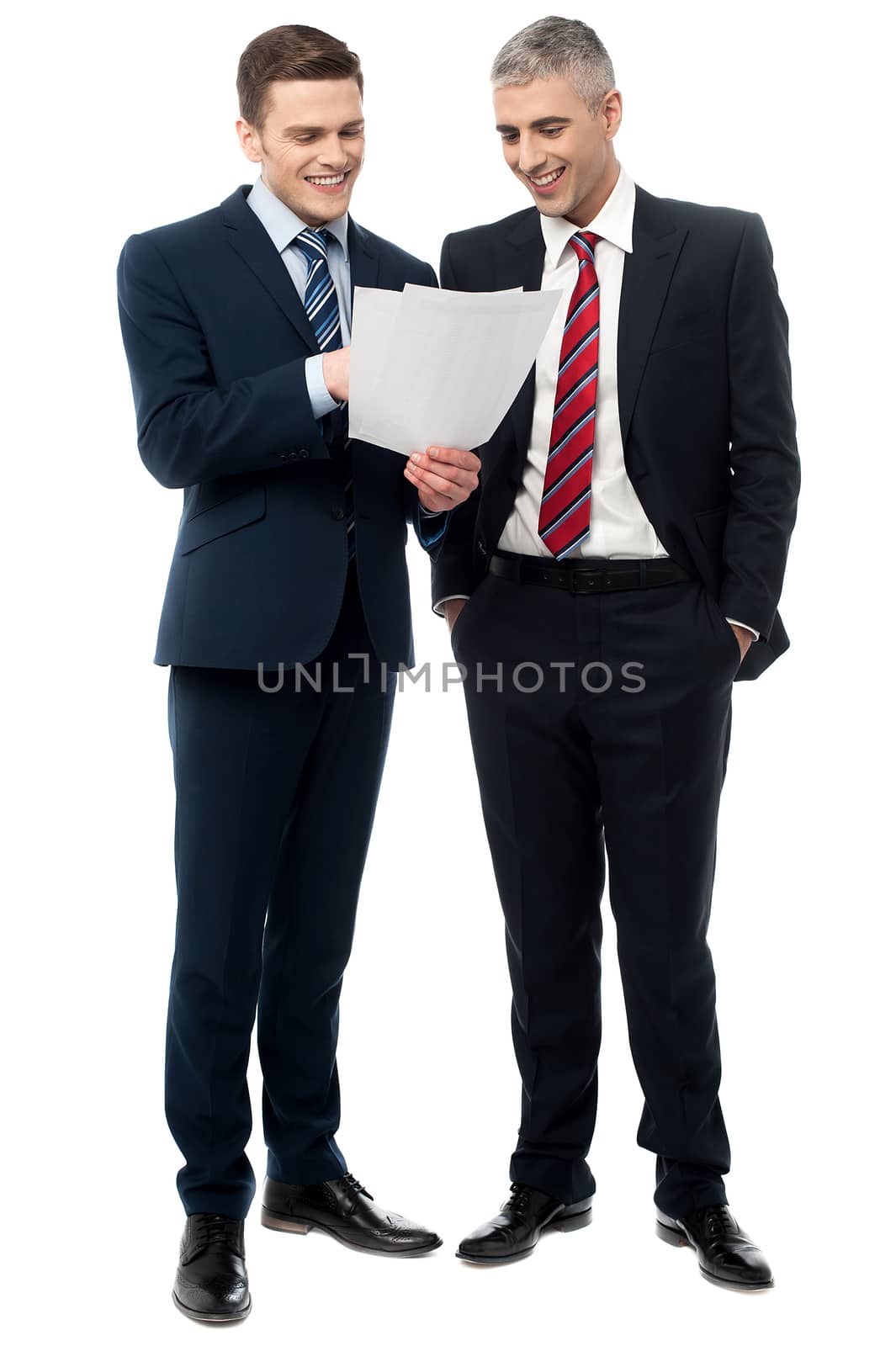 Businessmen evaluating deal documents by stockyimages