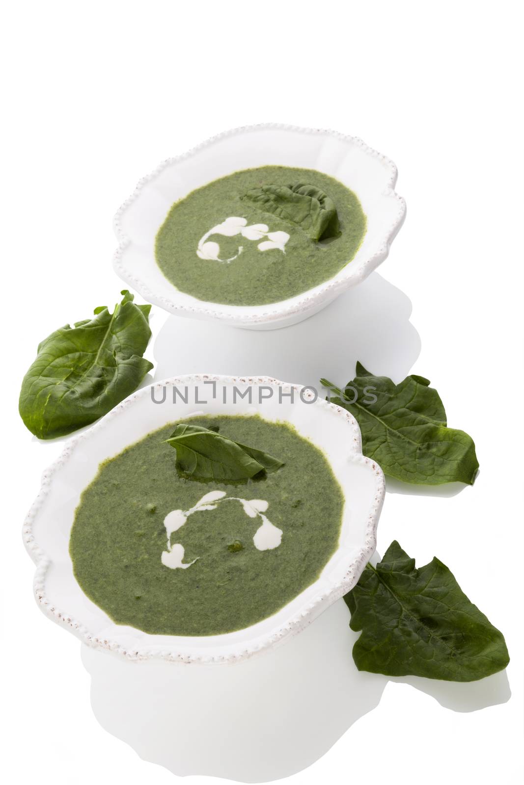 Delicious spinach soup with fresh spinach leaves isolated on white background. Healthy soup eating.