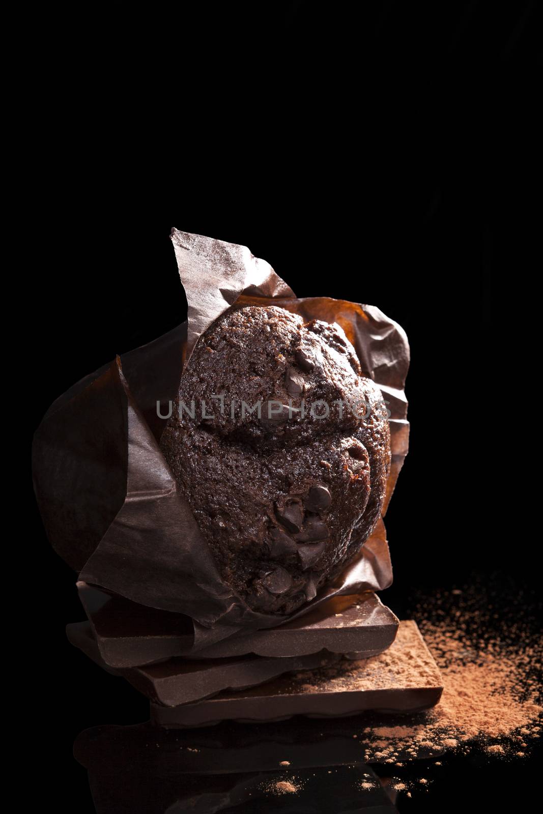 Chocolate muffin, Delicious chocolate muffin on black background with chocolate bar and cocoa powder. Sweet dessert. 