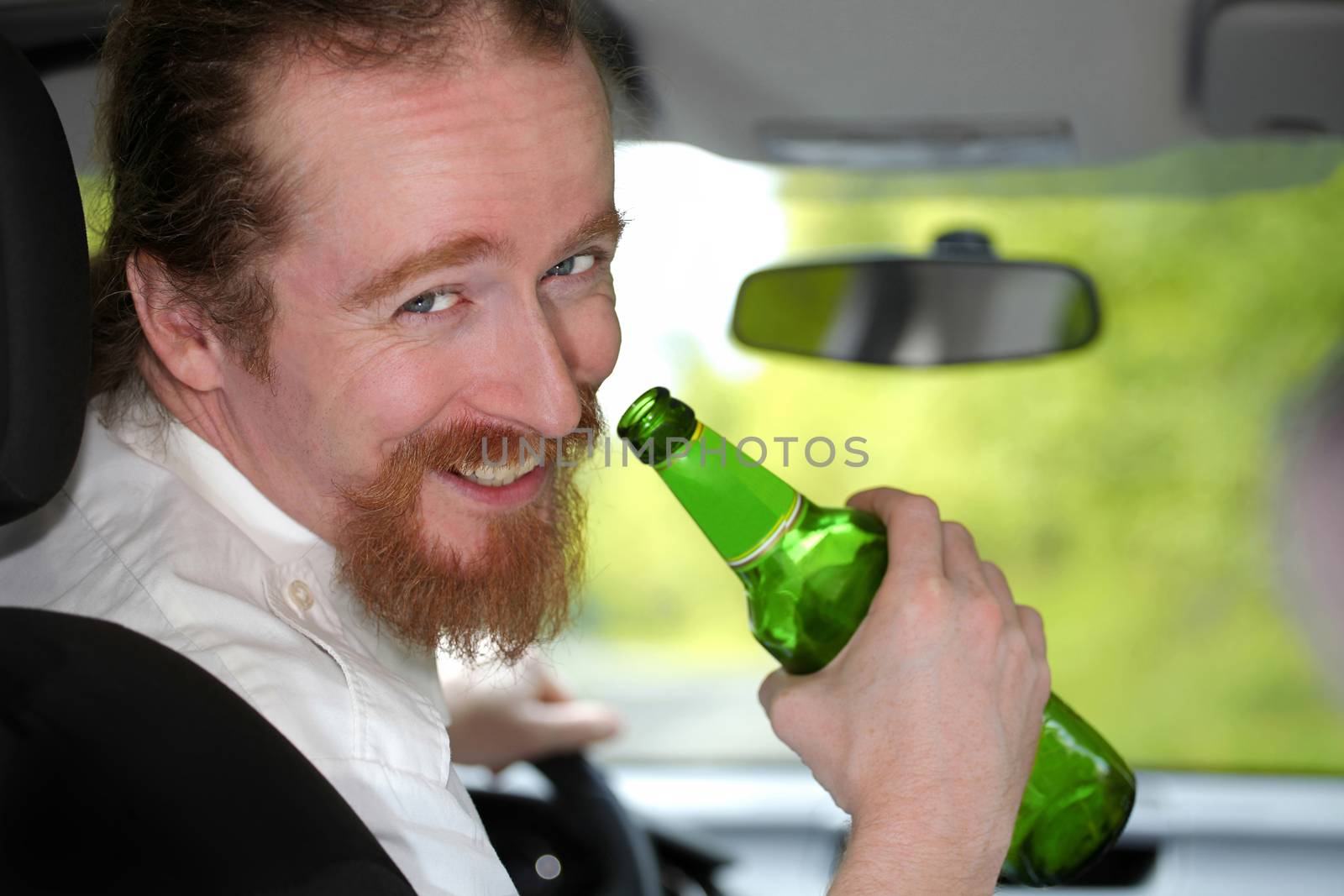 Drunk man in car with a bottle beer by vladacanon
