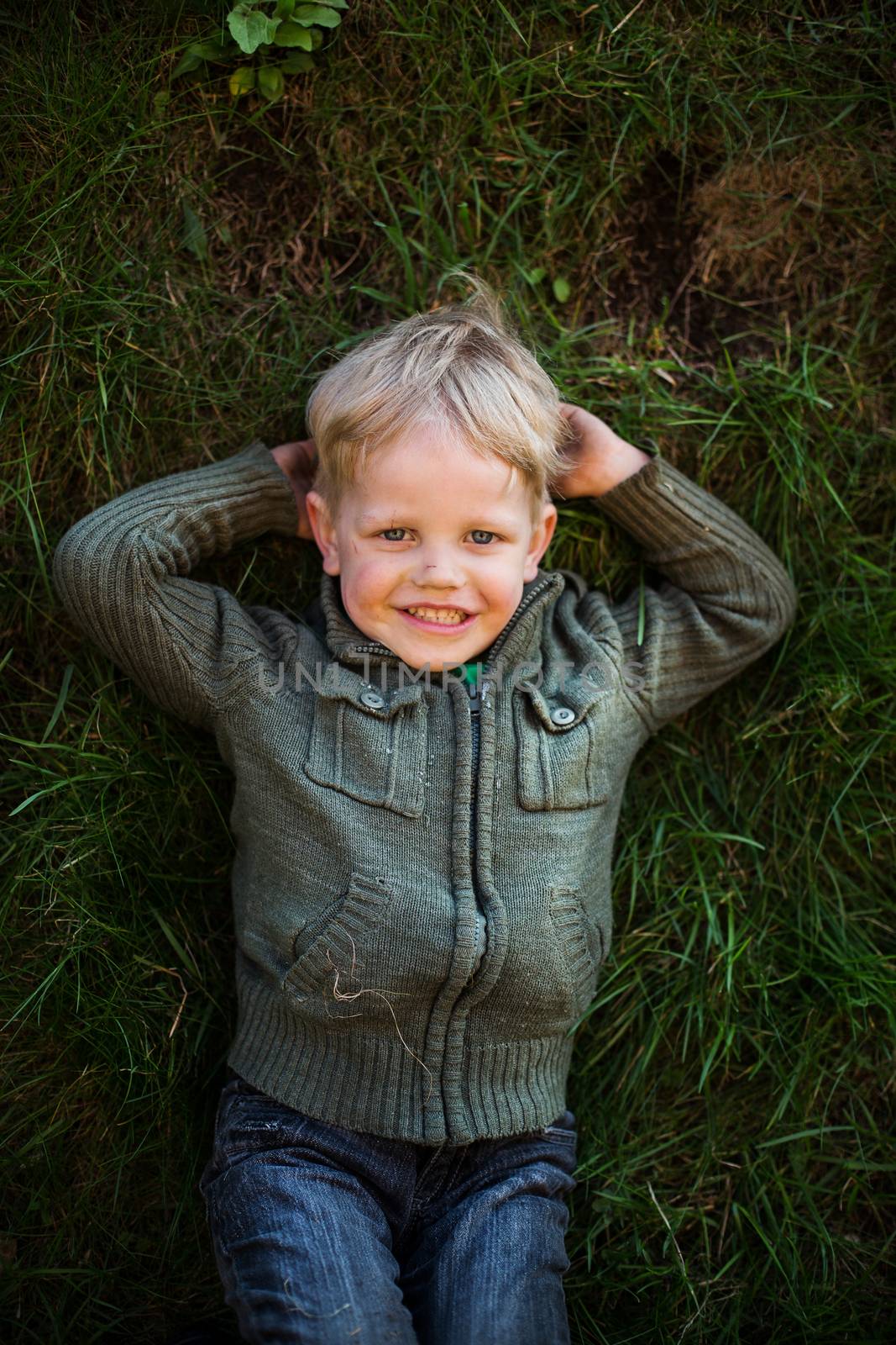 Portrait of a little boy lying on grass and smiling