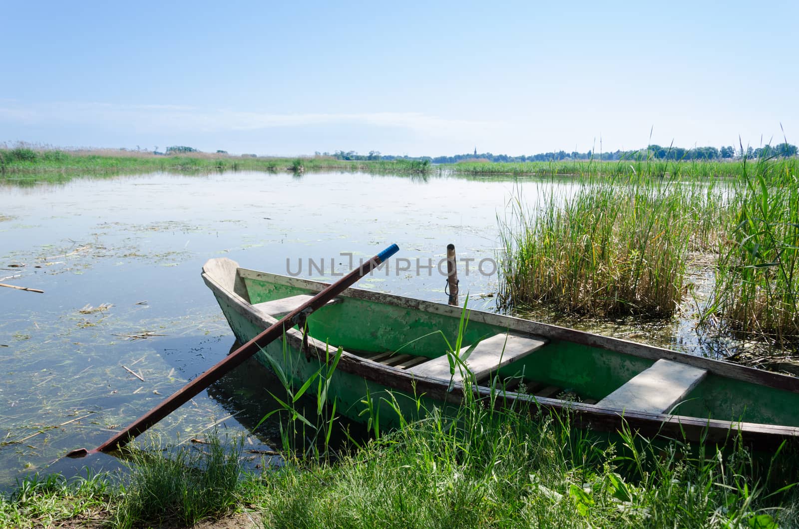 old boat scratched paint with oars coast on spring by sauletas