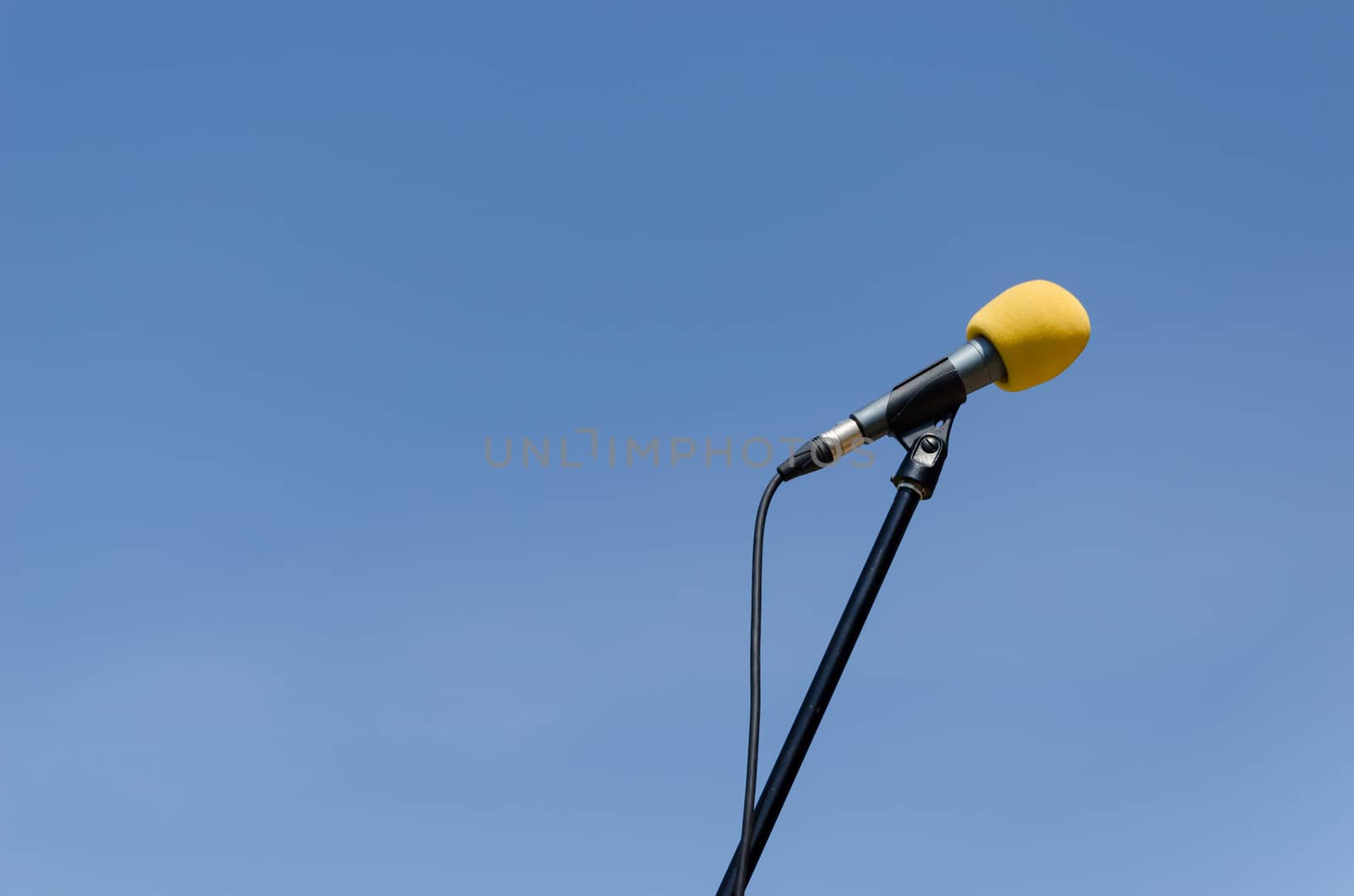 yellow microphone with stand on blue sky background