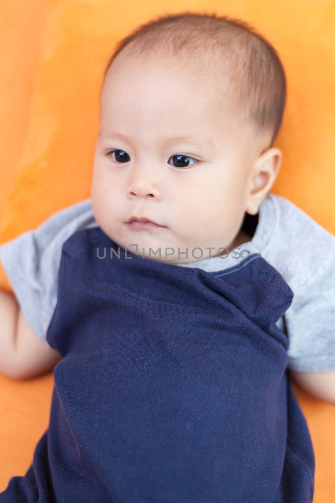 Baby boy.child Asian., And is lying on the orange sofa