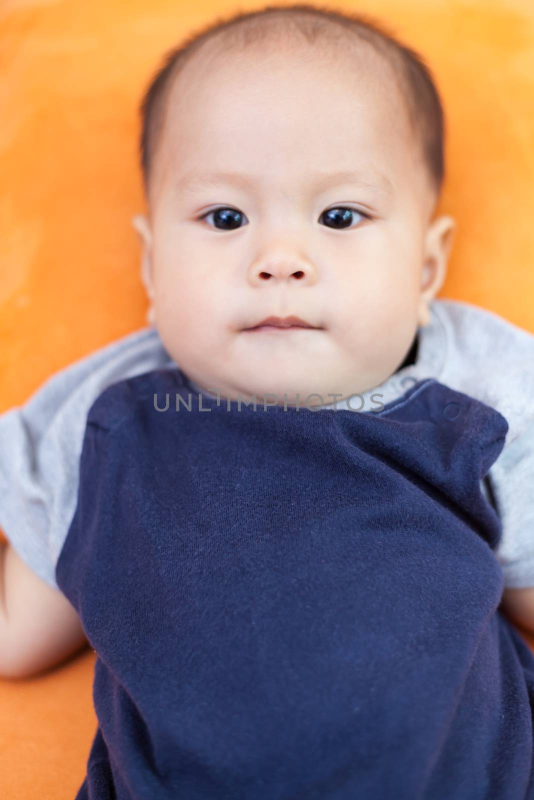 Baby boy.child Asian., And is lying on the orange sofa