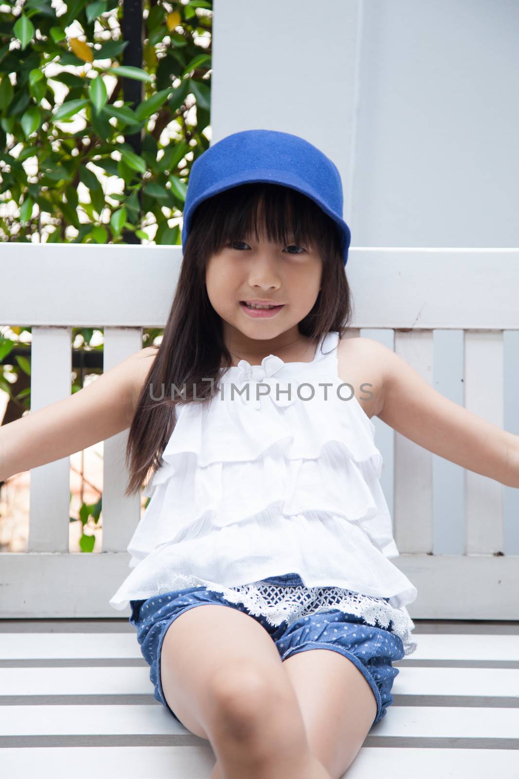 girl sitting on a swing Blue hat sitting on white wooden swings.