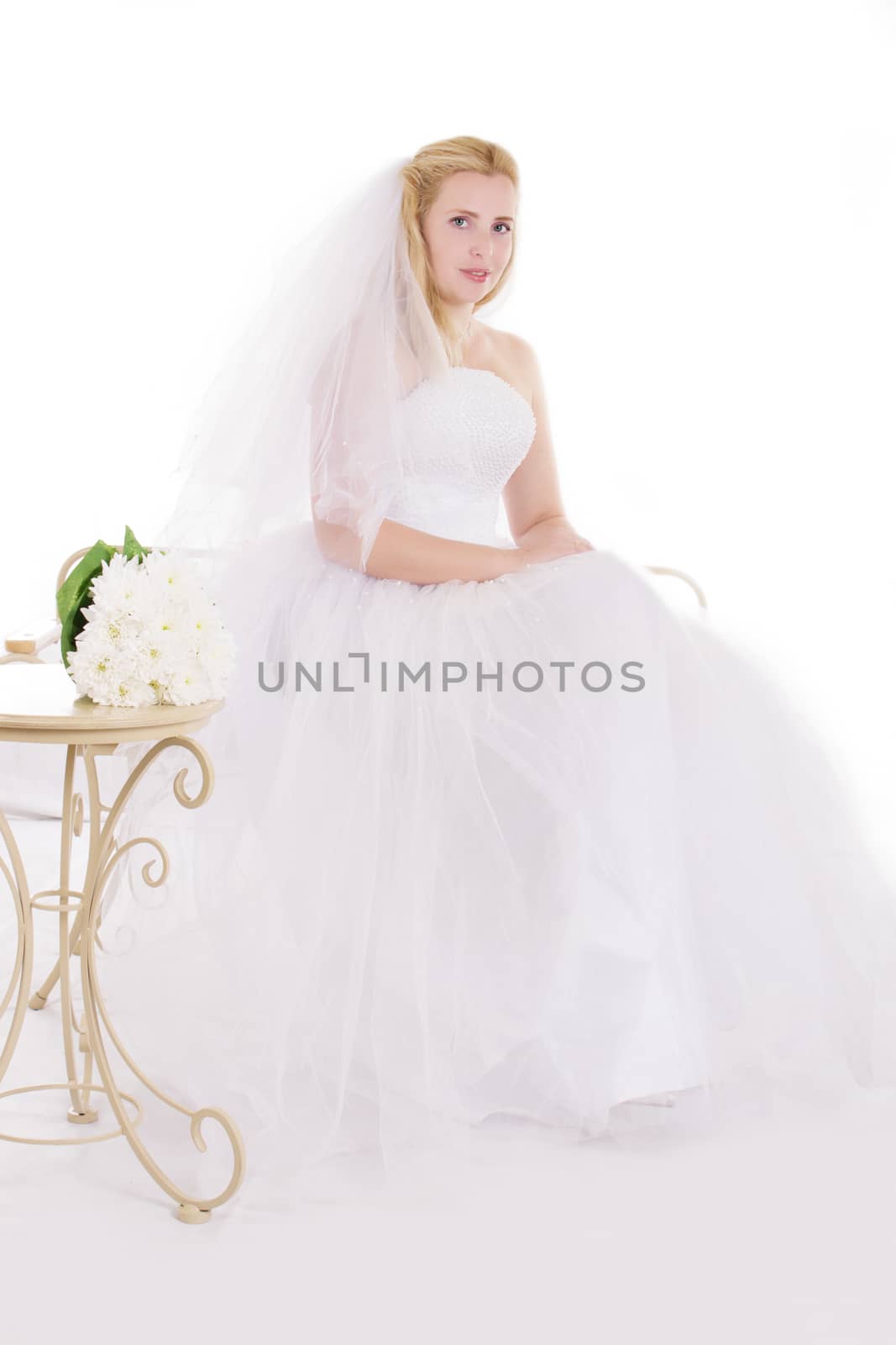 Blonde bride sitting with bouquet isolated on white