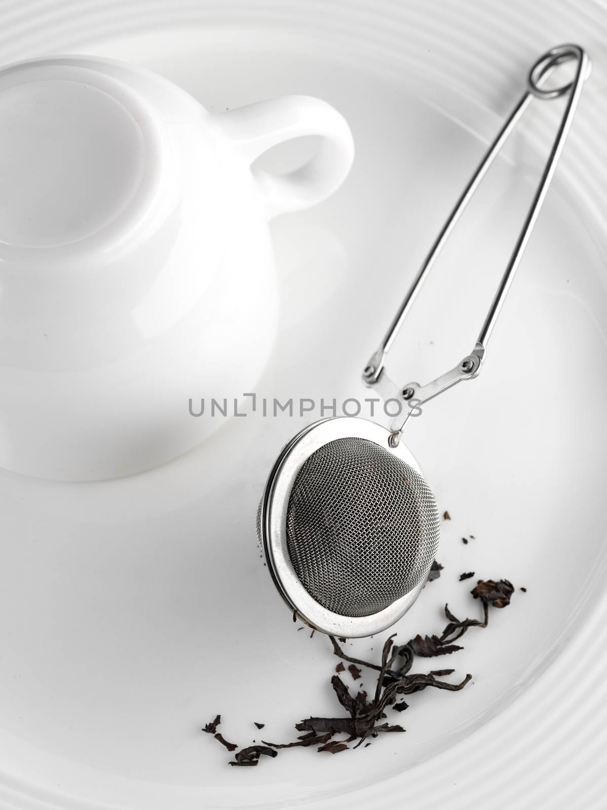 dry tea, strainer, cup on white plate