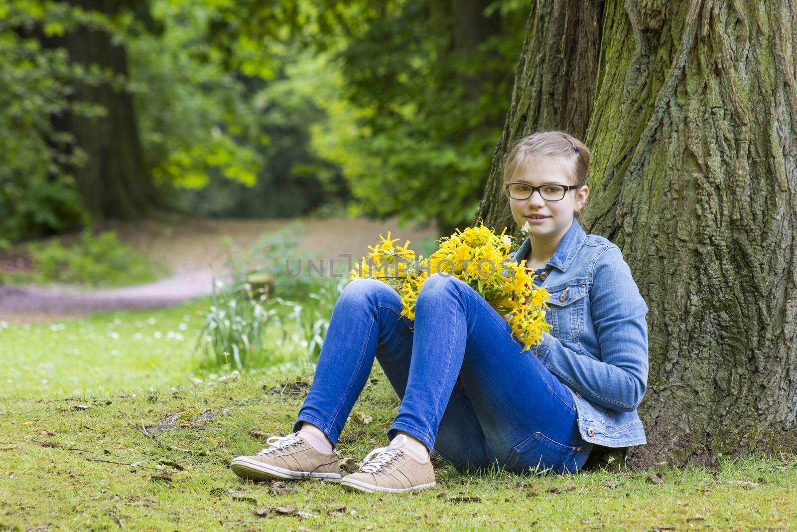 Smiling girl with big bouquet of spring flowers sitting in the p by miradrozdowski