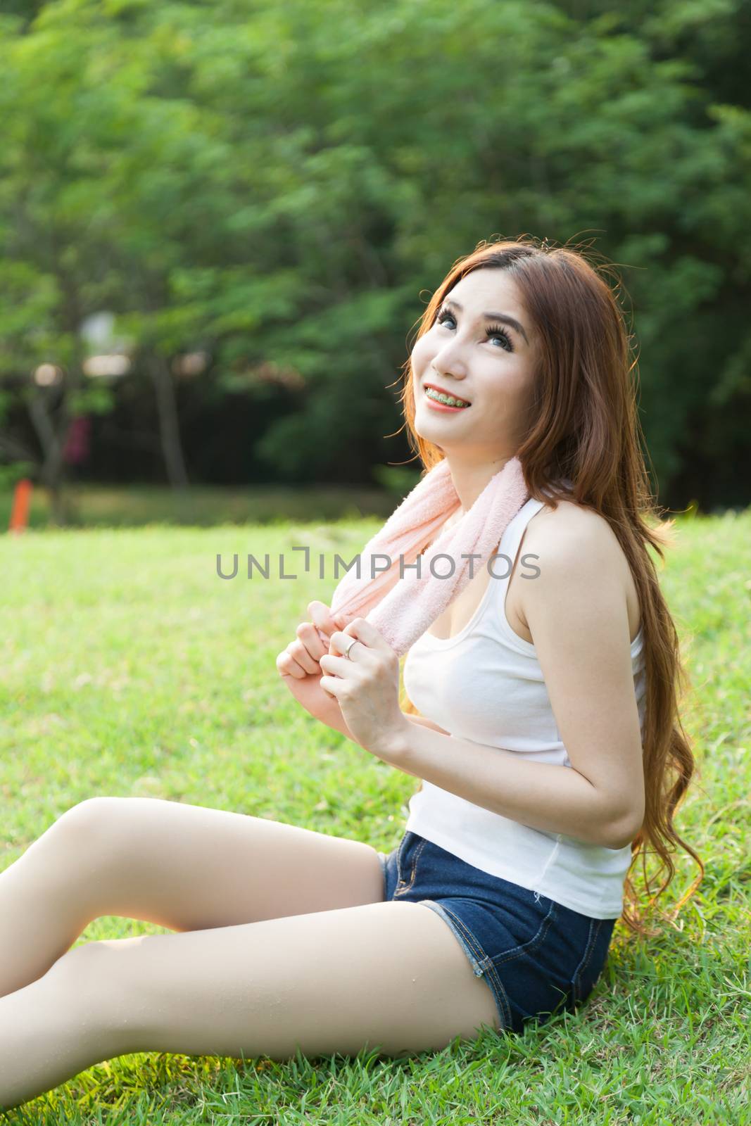 Woman sitting tired after jogging. Located on the lawn in the park.