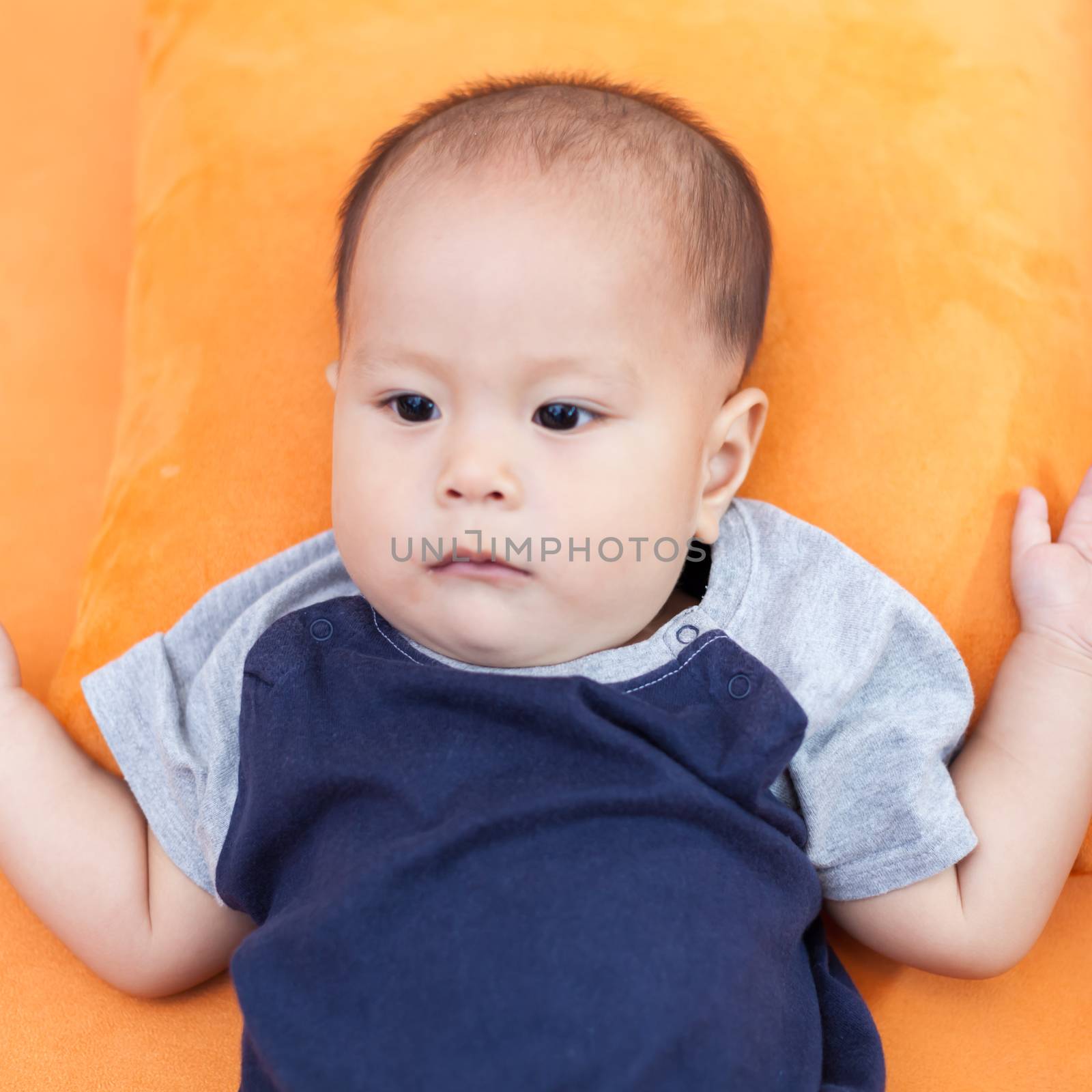 Baby boy.child Asian., And is lying on the orange sofa