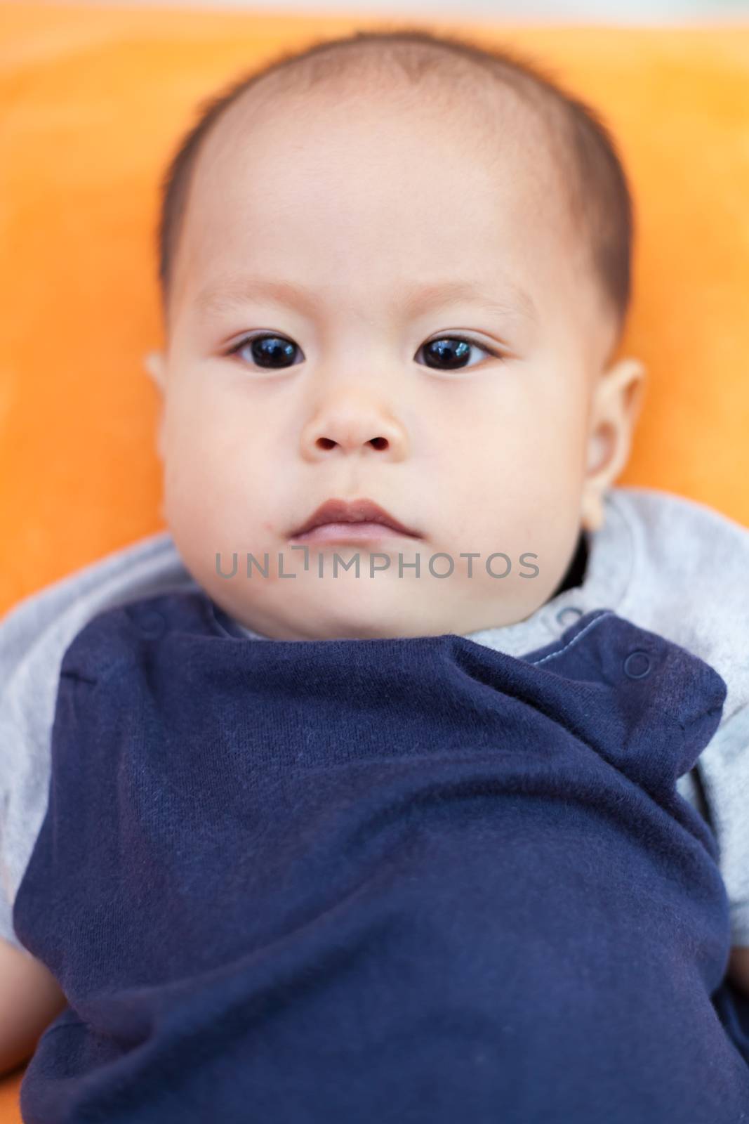 Baby boy.child Asian., And is lying on the orange sofa