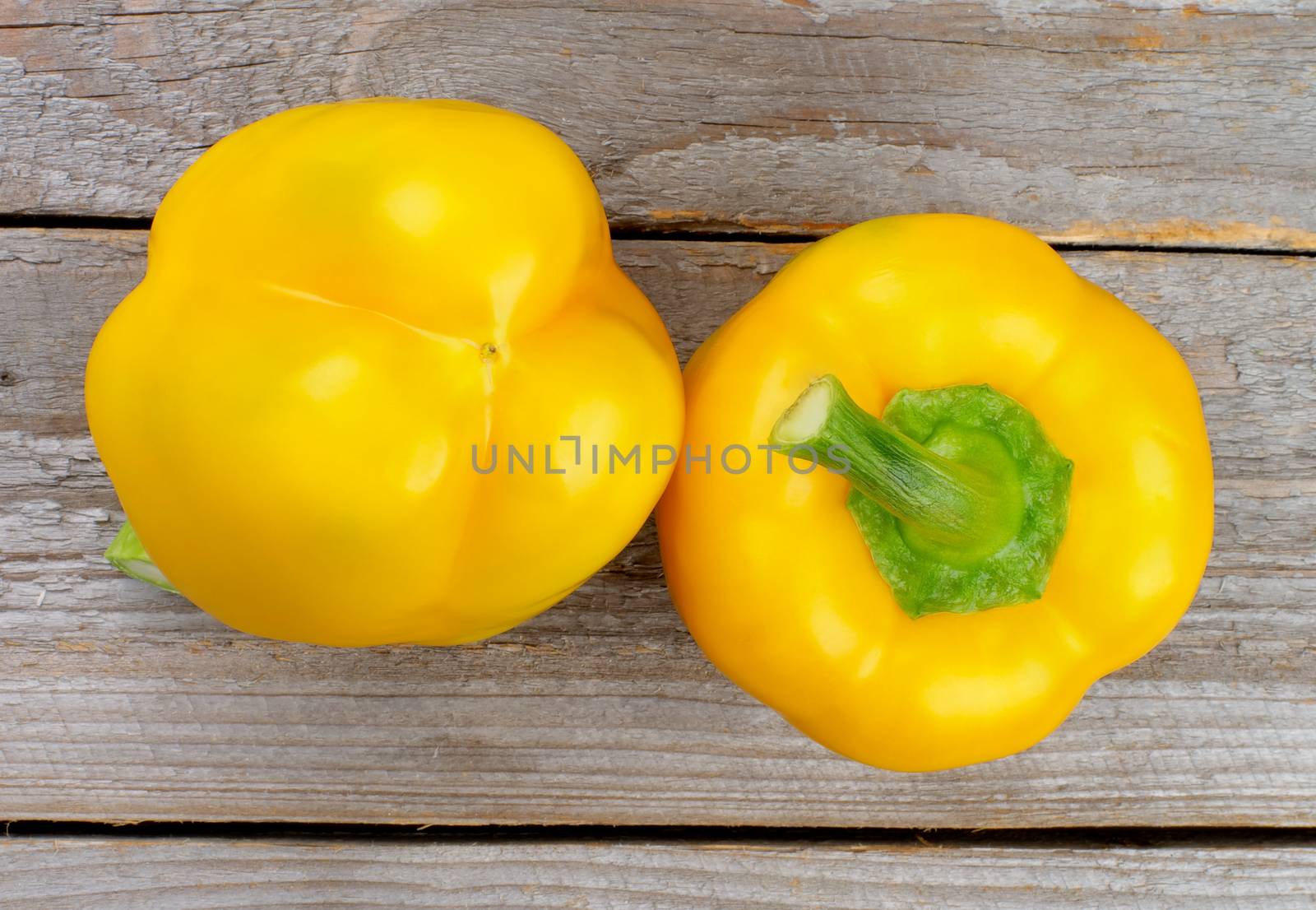 Two Ripe Yellow Bell Peppers isolated on Rustic Wooden background. Top View