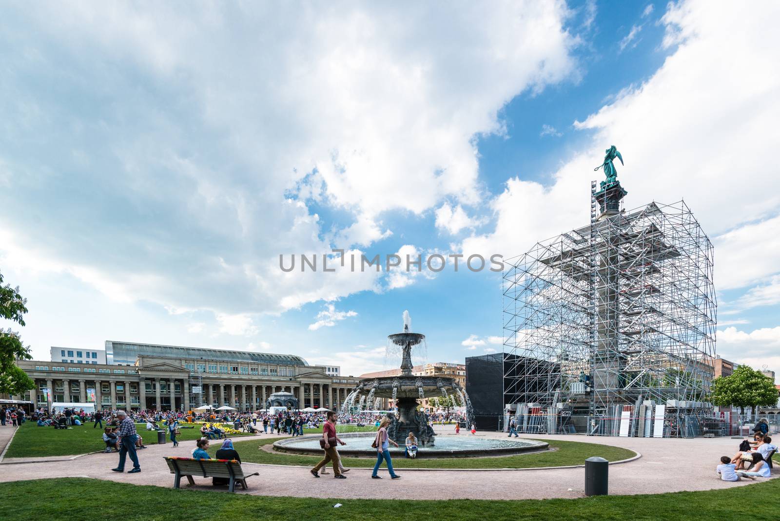 STUTTGART, GERMANY - APRIL 24, 2014: People are enjoying a great sunny spring day on Schlossplatz (Castle Square) in the city center of Stuttgart on April, 26,2014 in Stuttgart, Germany. The square features the 30 meters high Jubilee Pillar carrying a portrait of goodness Concordia that is currently undergoing major renovations.