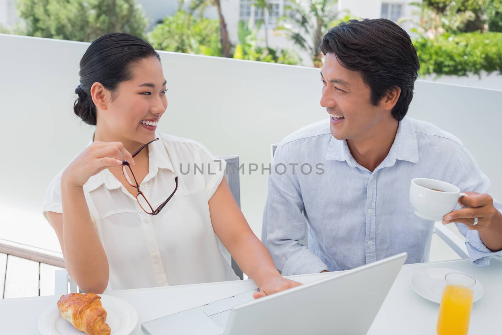 Smiling couple having breakfast together using laptop by Wavebreakmedia