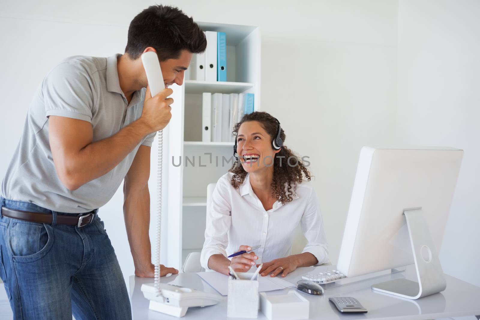 Casual business team laughing together at desk by Wavebreakmedia