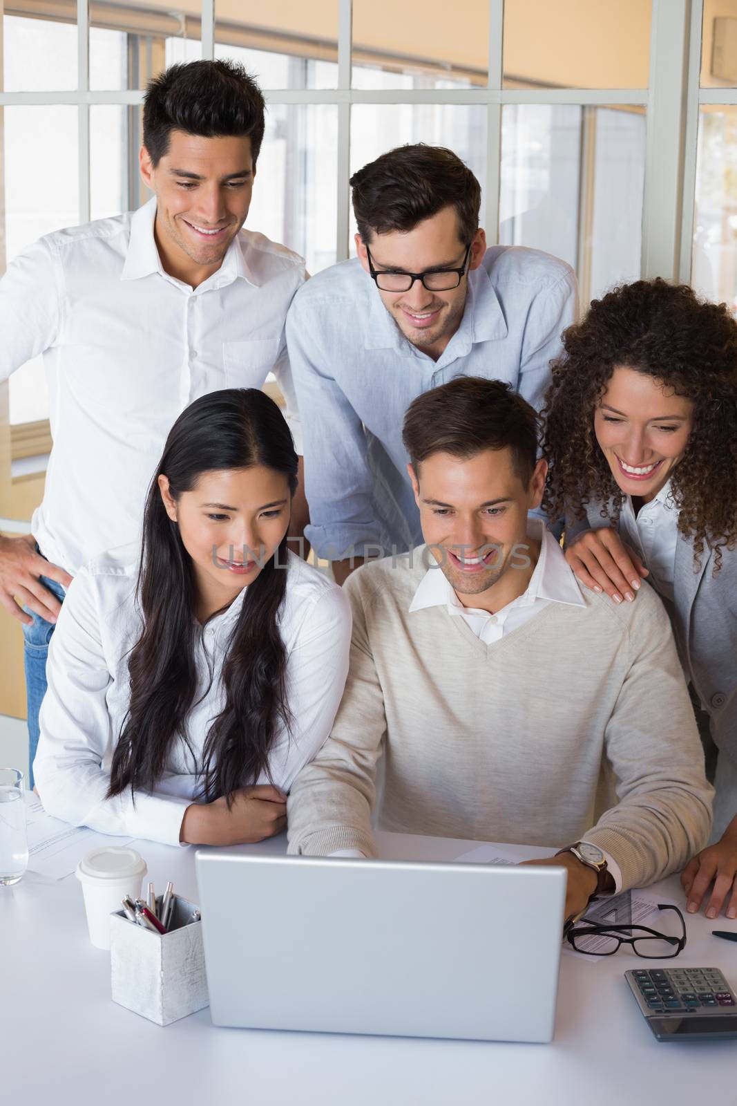 Casual smiling business team having a meeting using laptop in the office