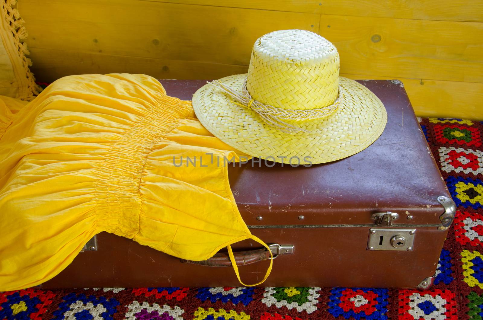 yellow dress and straw hat lying on old suitcase by sauletas