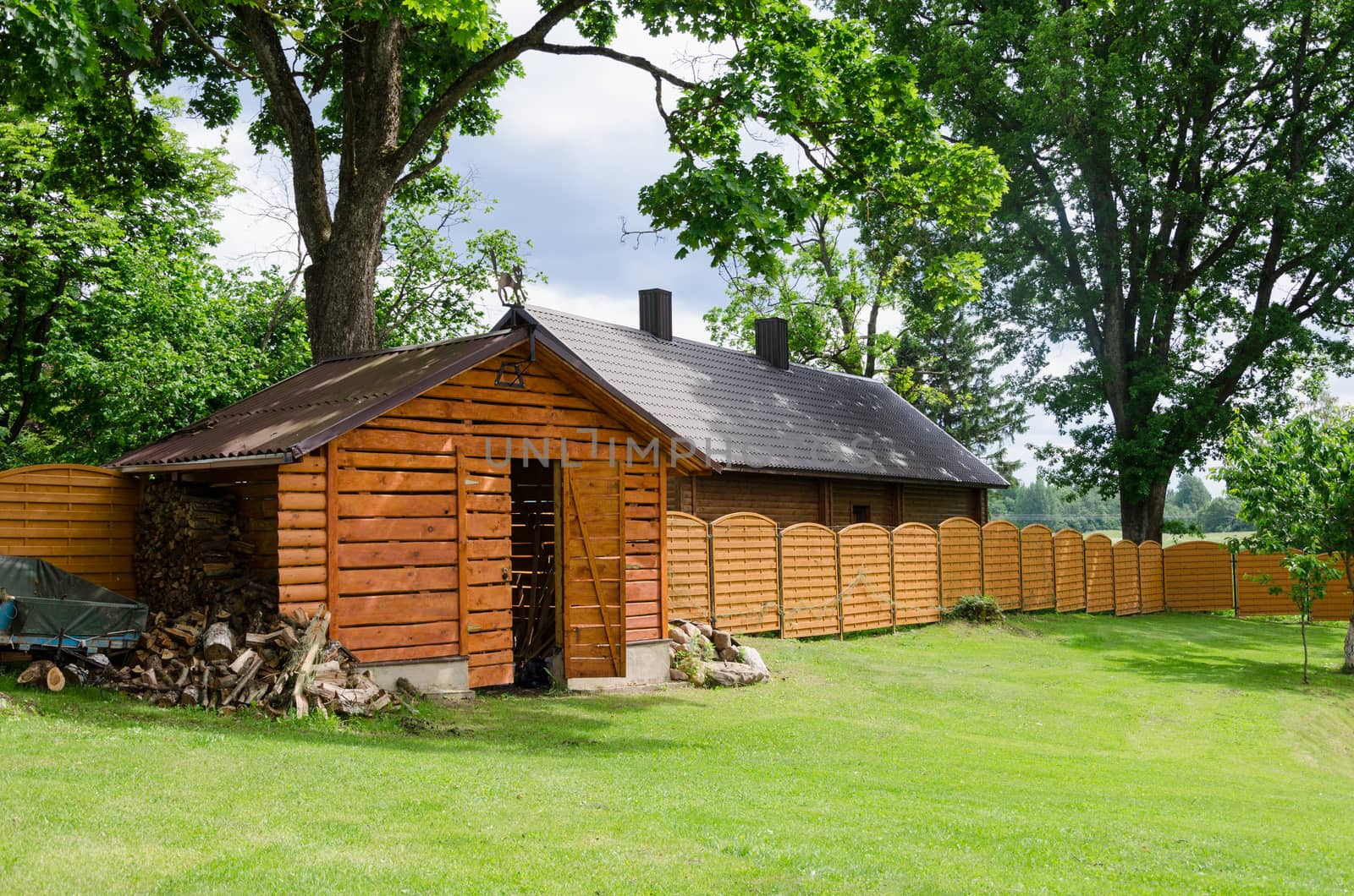 handmade woodshed in village along wooden fence by sauletas