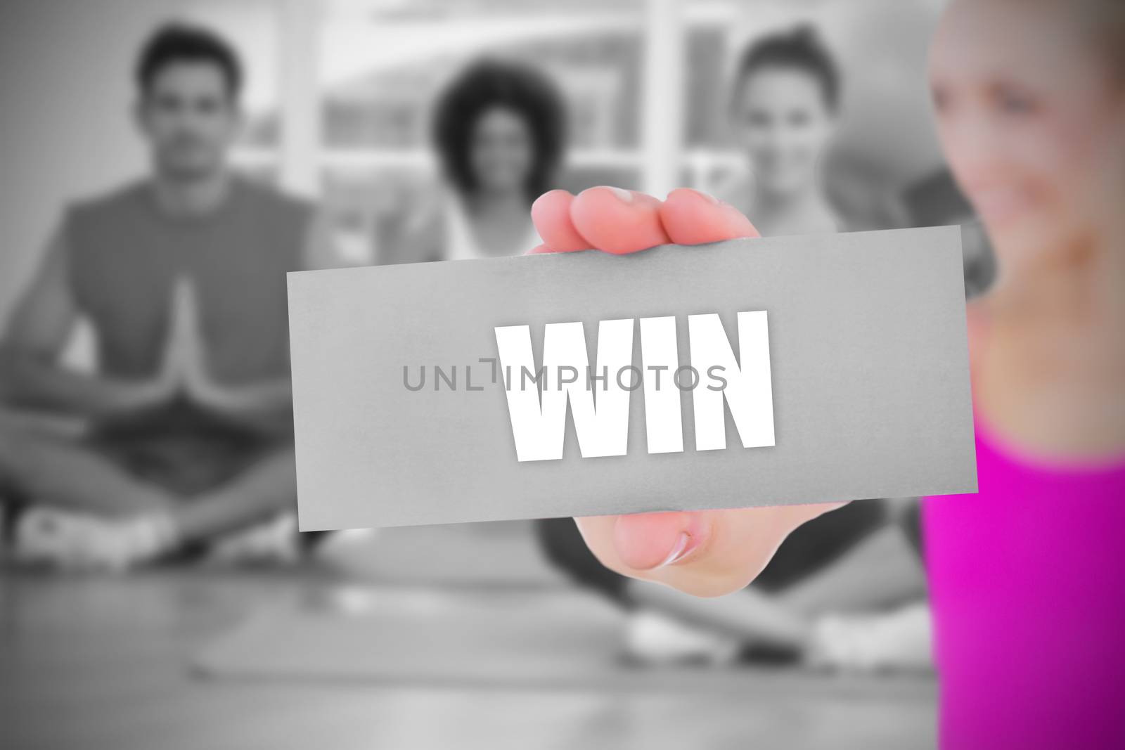 Fit blonde holding card saying win against yoga class in gym 