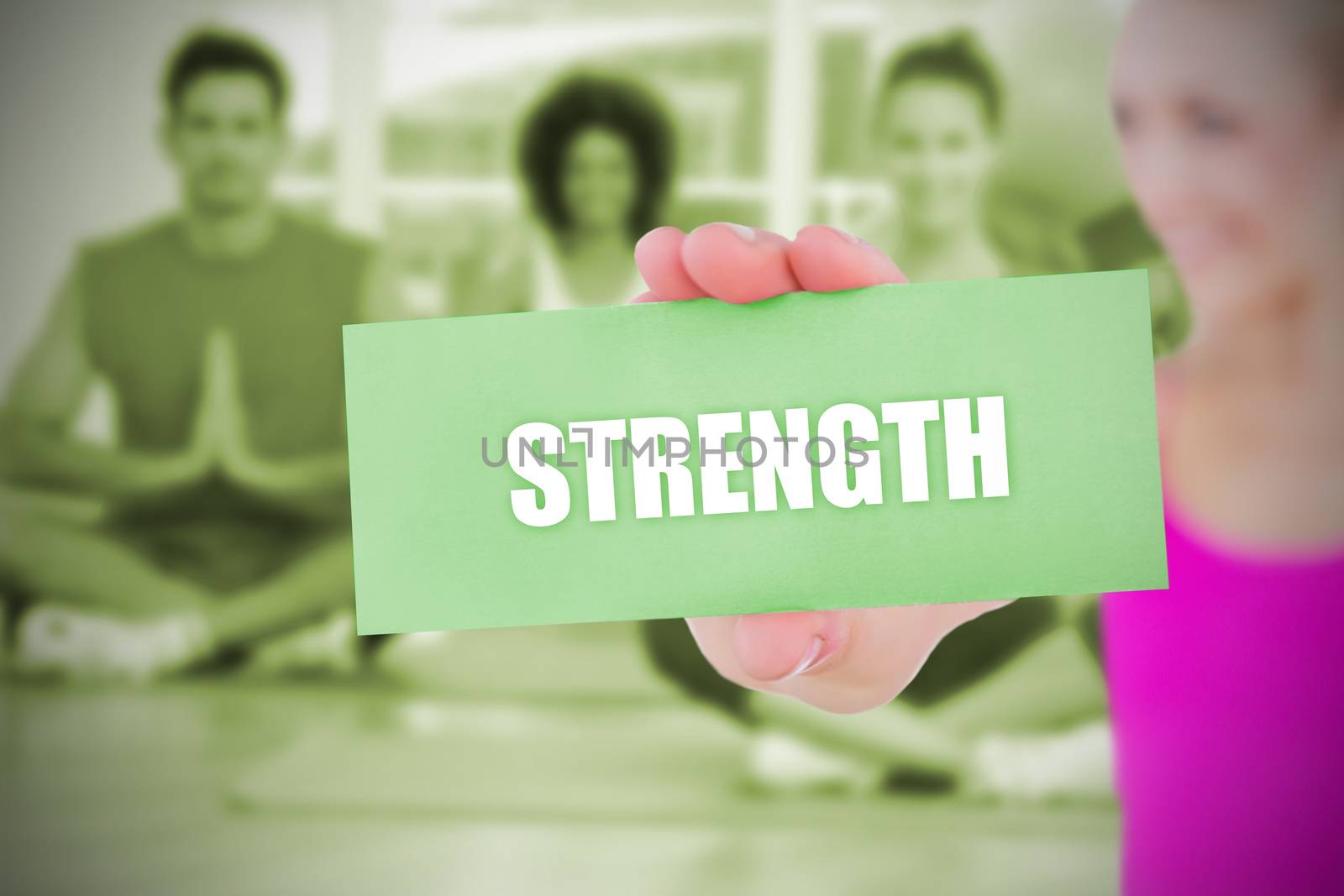 Fit blonde holding card saying strength against yoga class in gym 