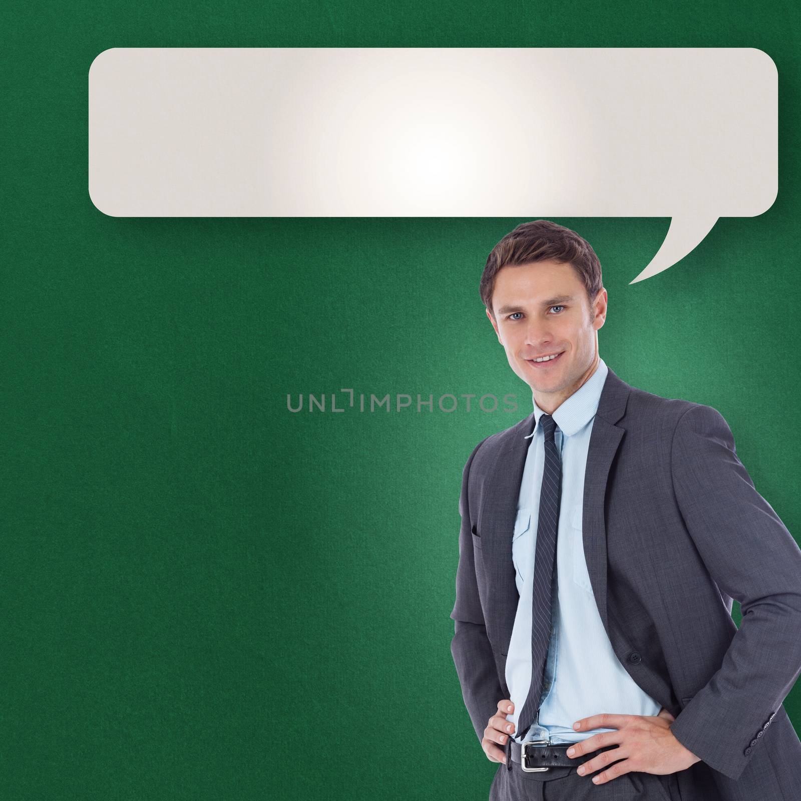 Smiling businessman with hands on hips against speech bubble