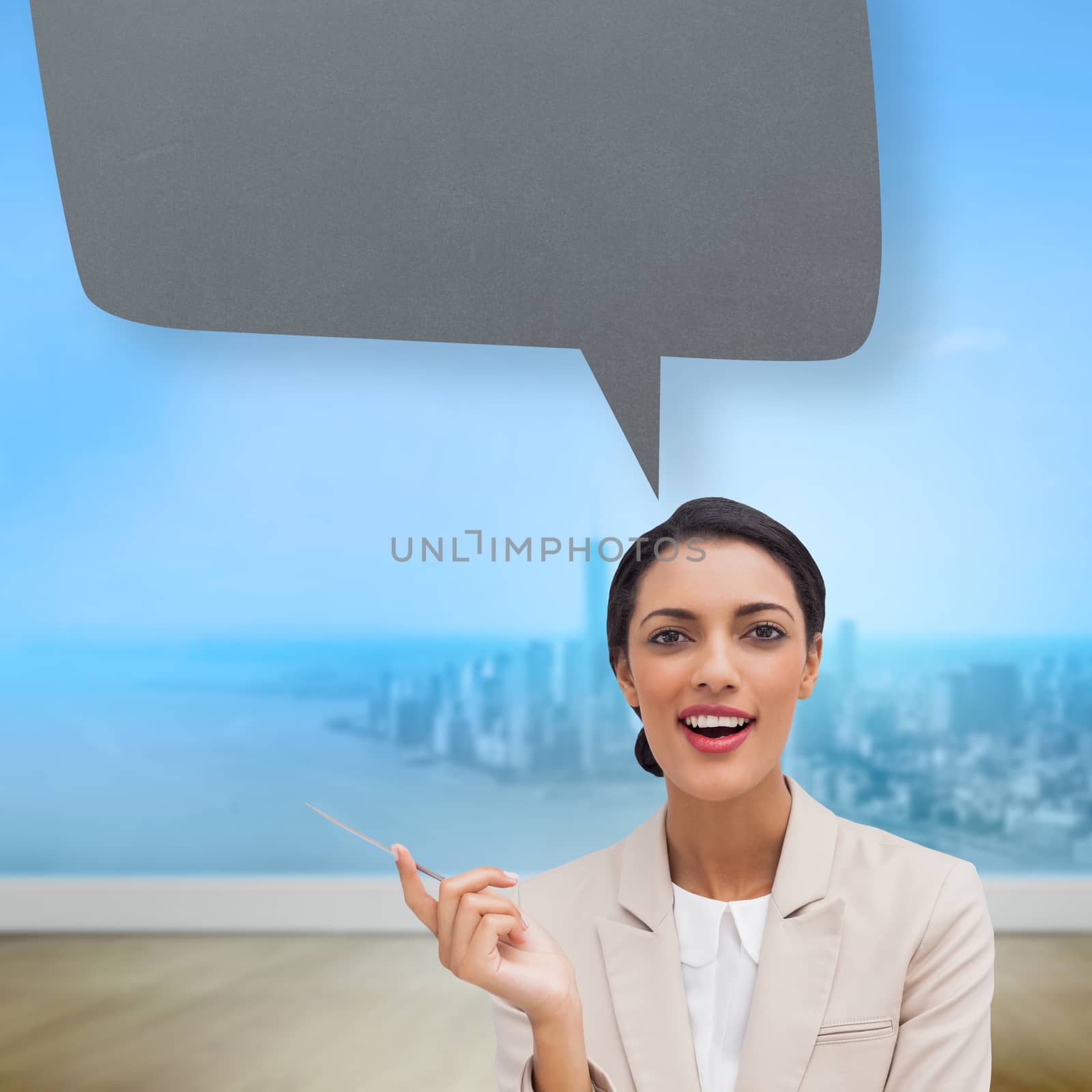 Smiling businesswoman holding a pen with speech bubble against city projection on wall