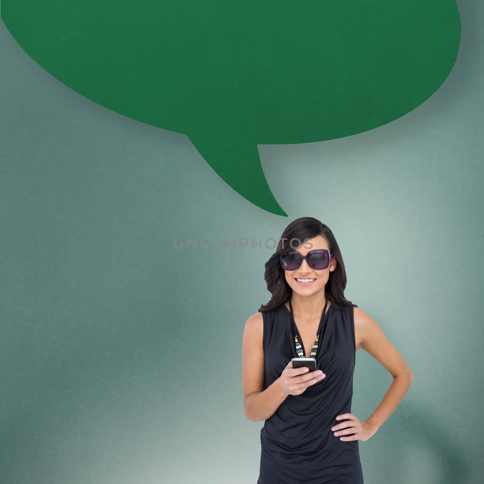 Composite image of happy brunette holding smartphone with speech bubble by Wavebreakmedia