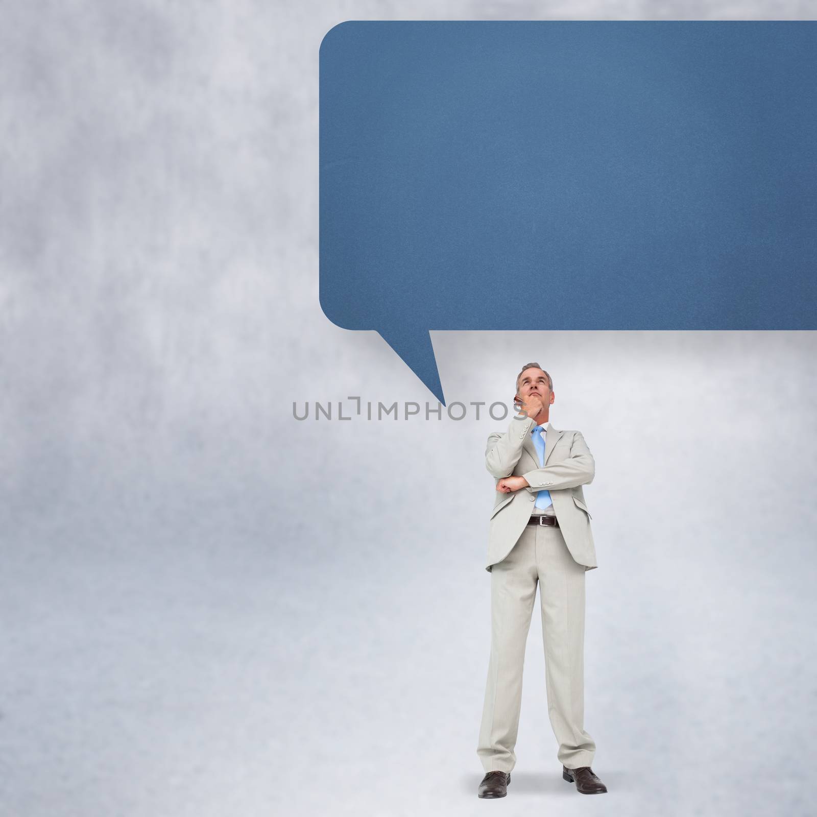 Thinking businessman with speech bubble against grey wall