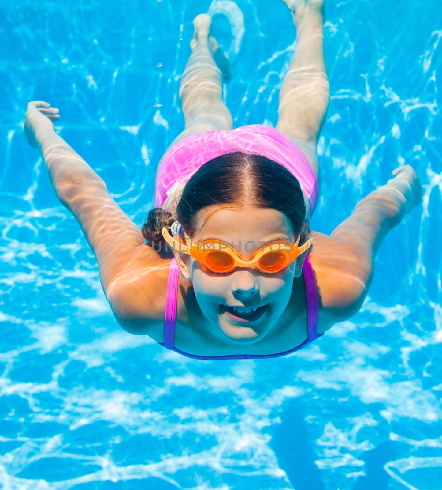 The cute girl swimming underwater and smiling