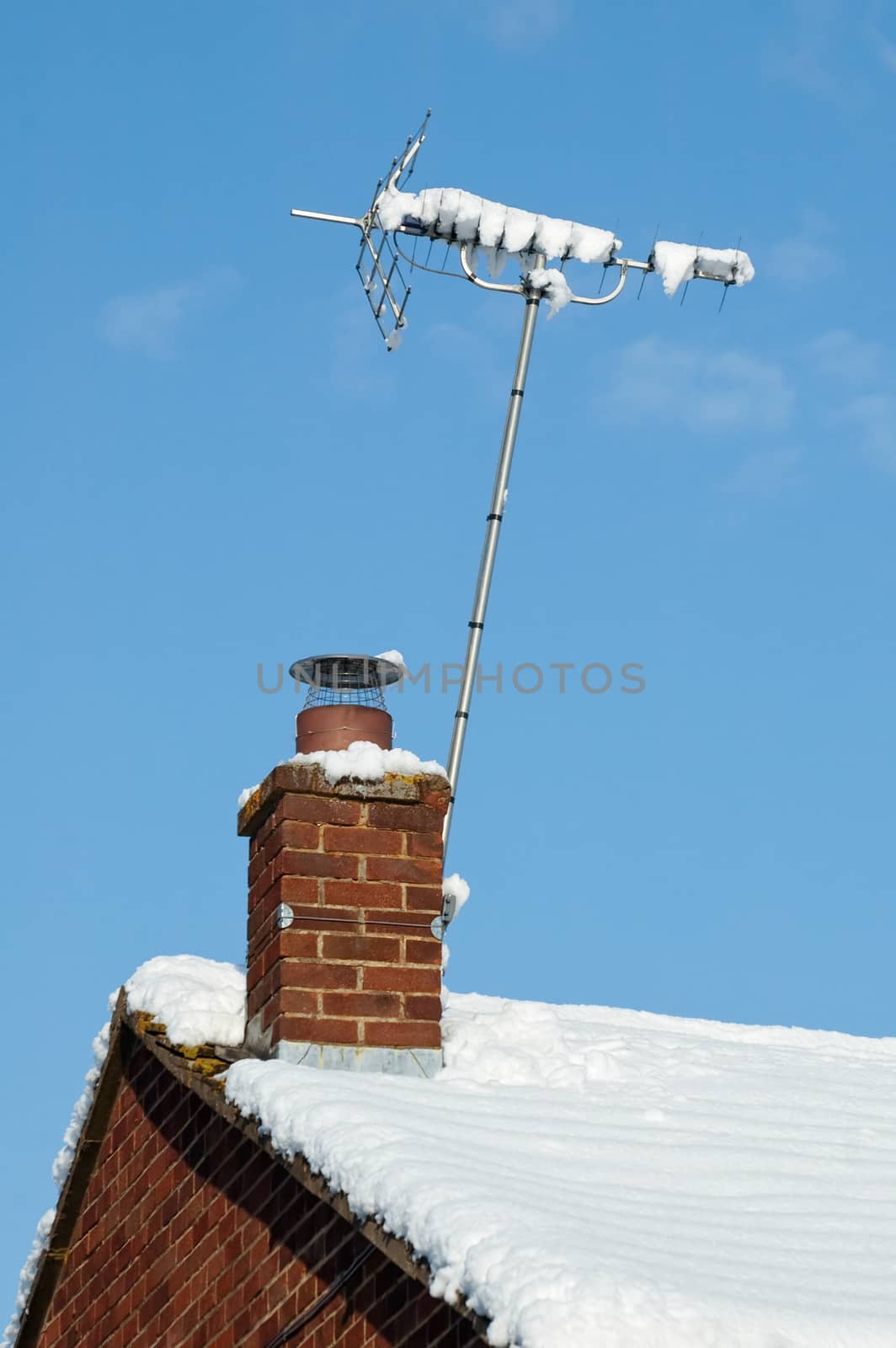 snow covered television aerial on wintry rooftop