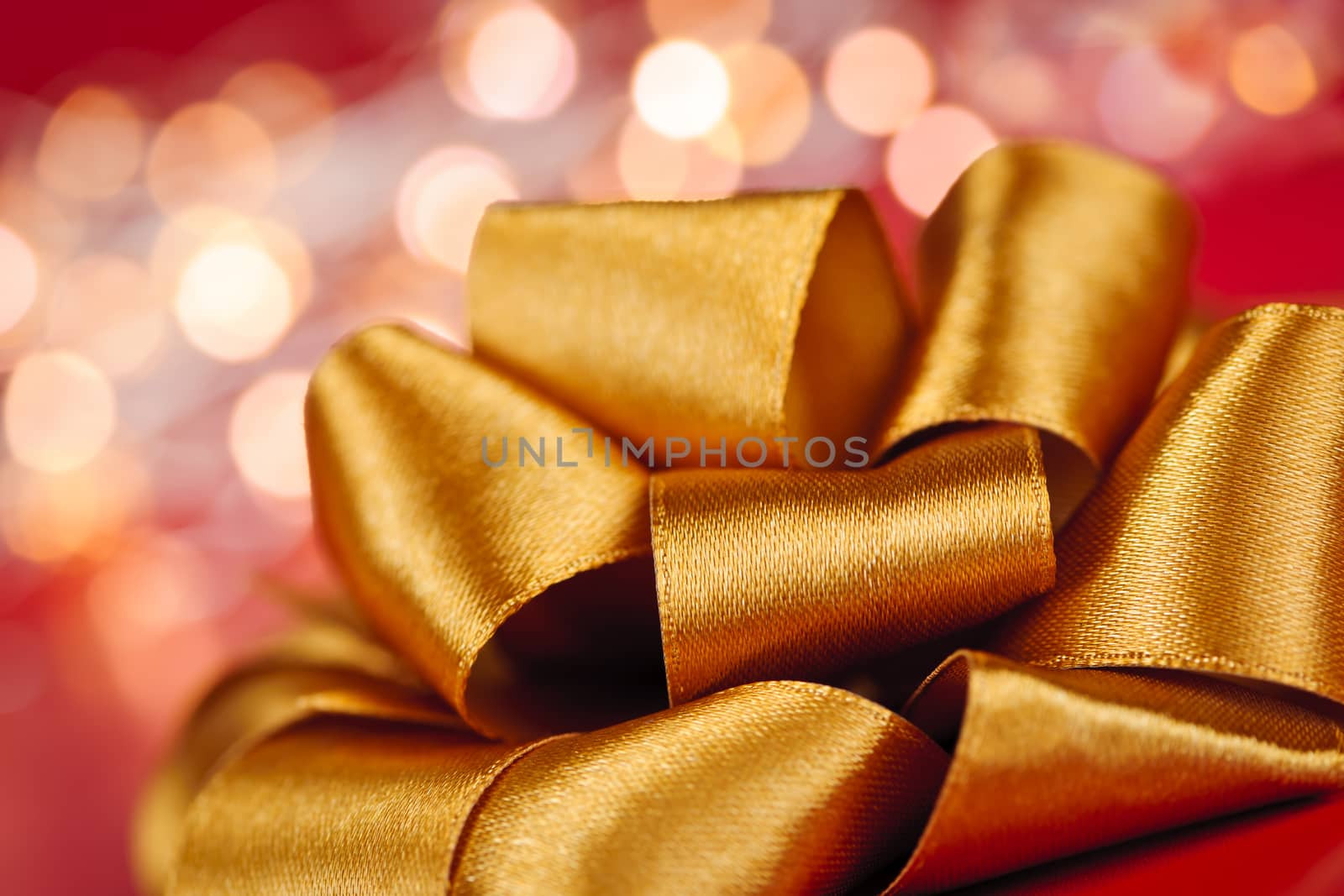 Golden ribbon gift bow closeup with festive lights