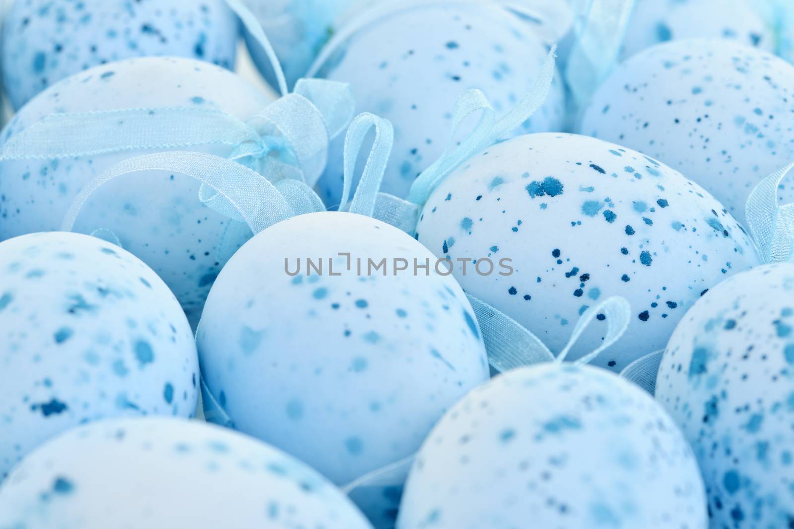Pale blue speckled painted Easter eggs with ribbons