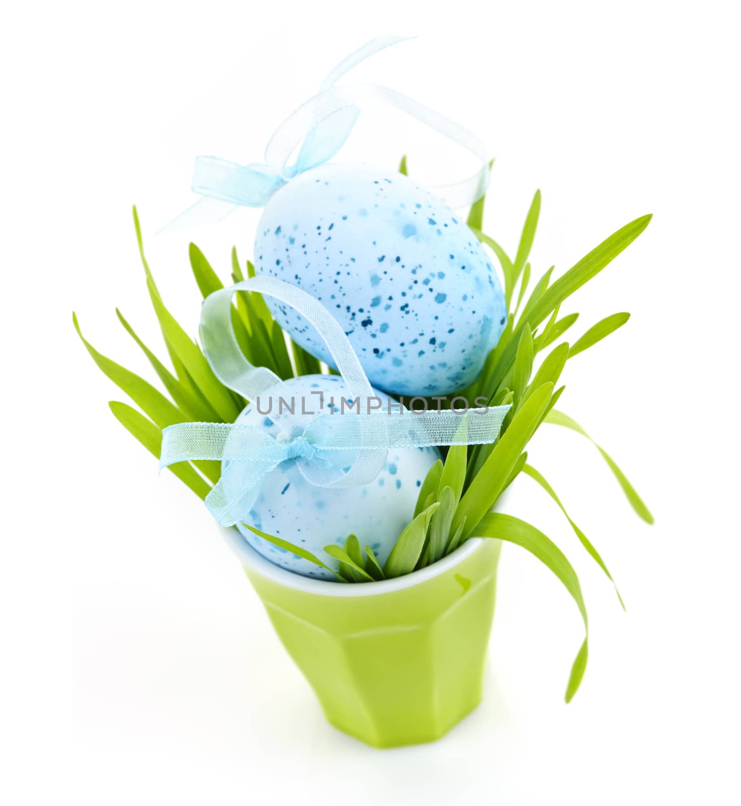 Blue Easter eggs arranged in cup with fresh green grass isolated on white