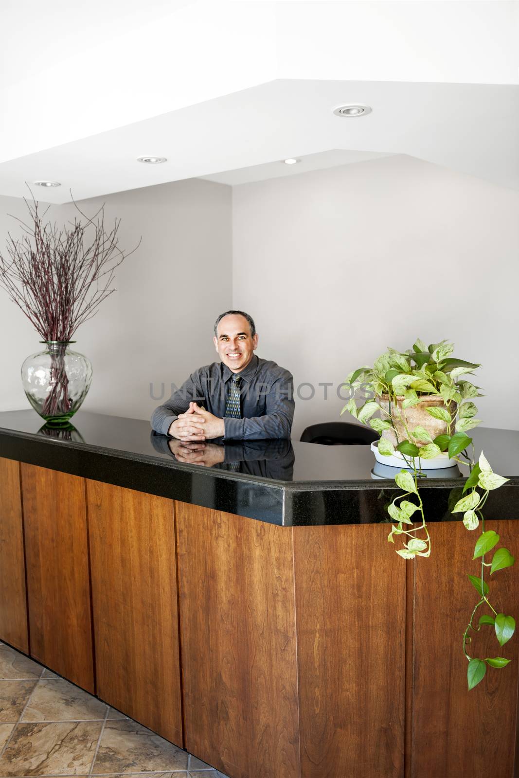 Smiling man standing at office reception by elenathewise