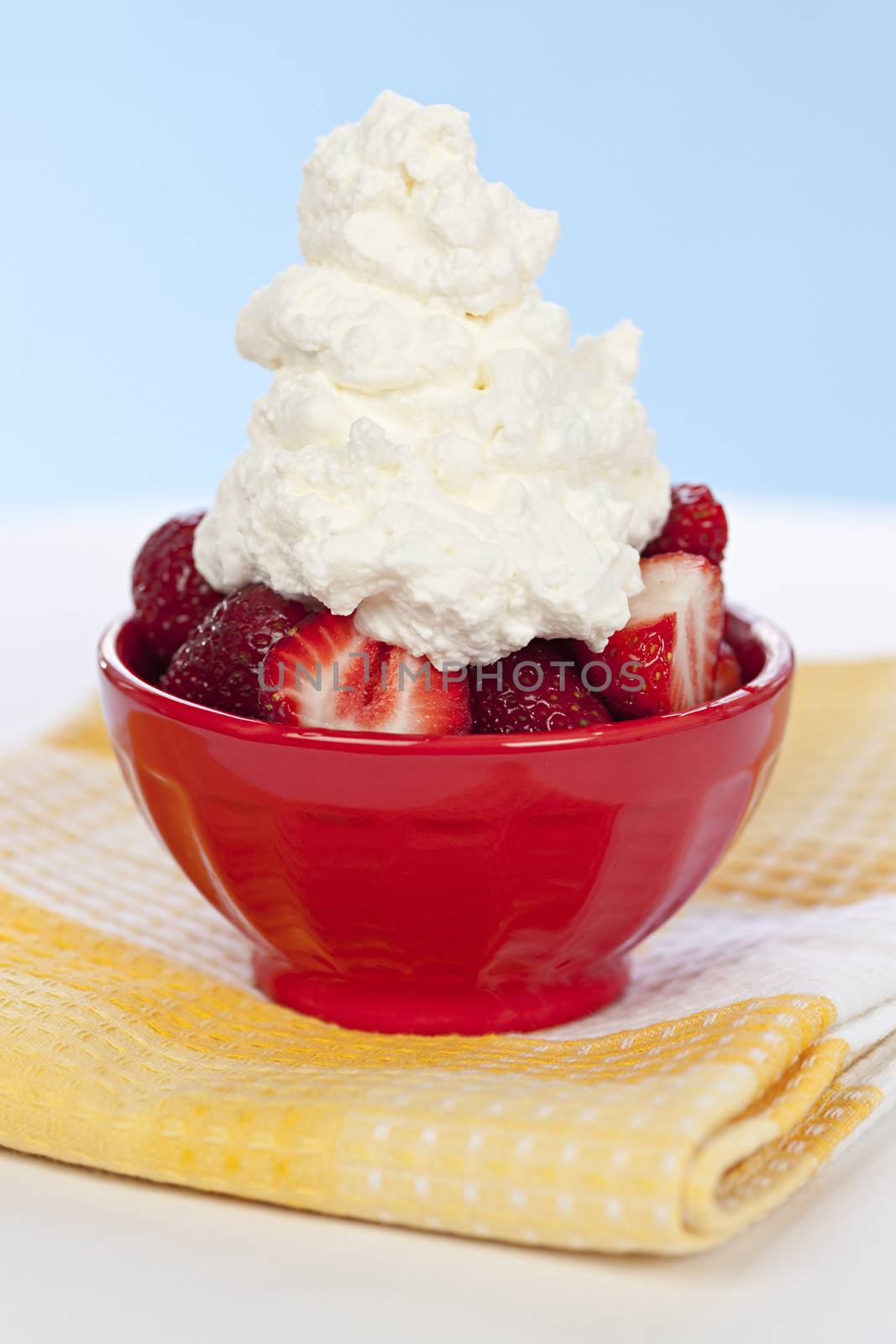Fresh strawberries with whipped cream in red bowl
