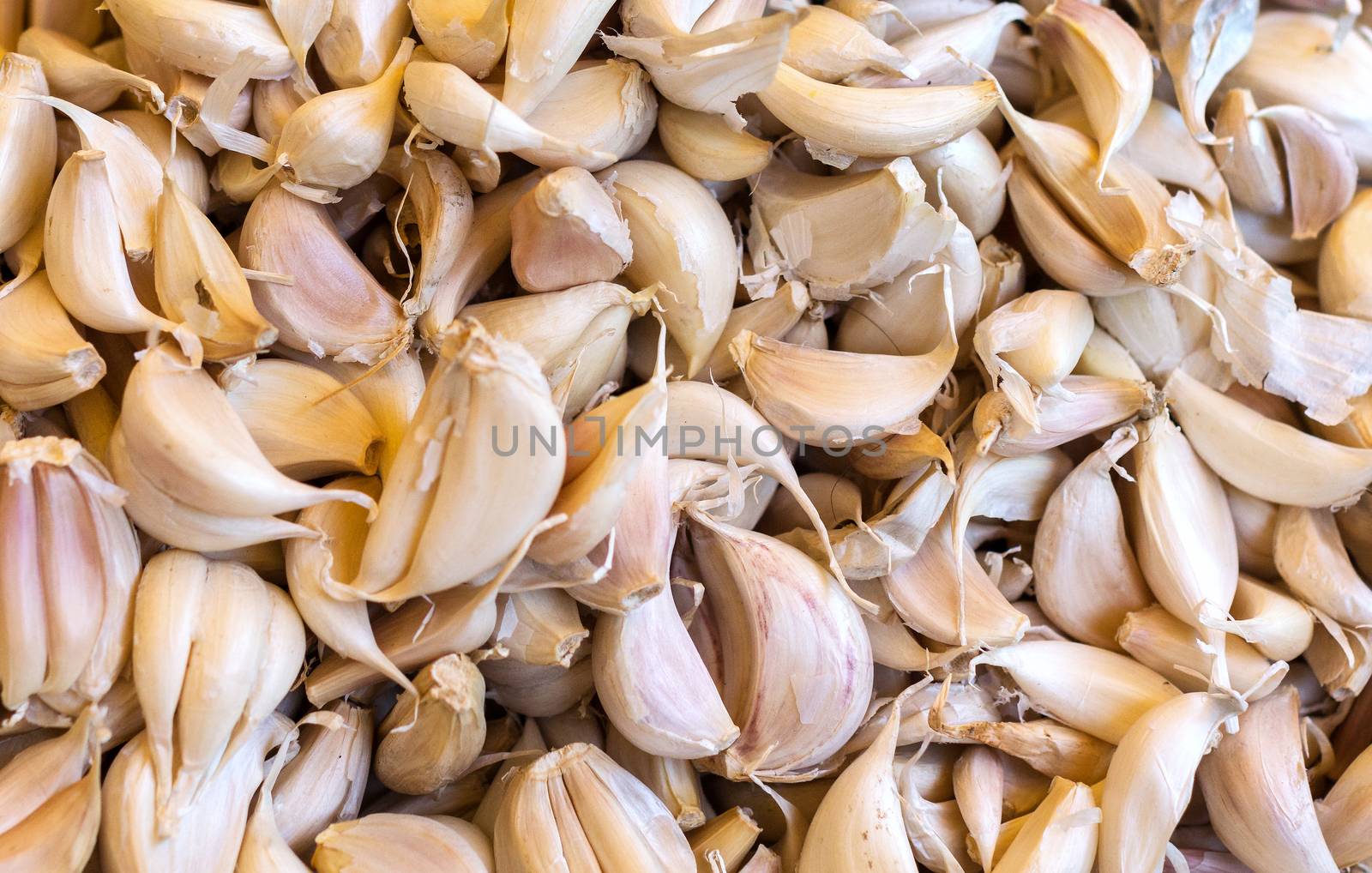 heap of garlic cloves on display at the market. by Claudine