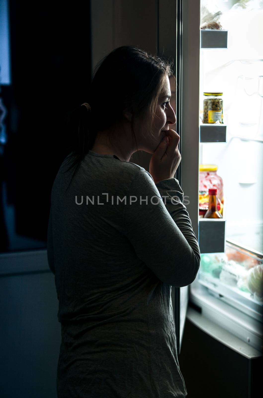 Portrait of woman in pajamas opening refrigerator at night