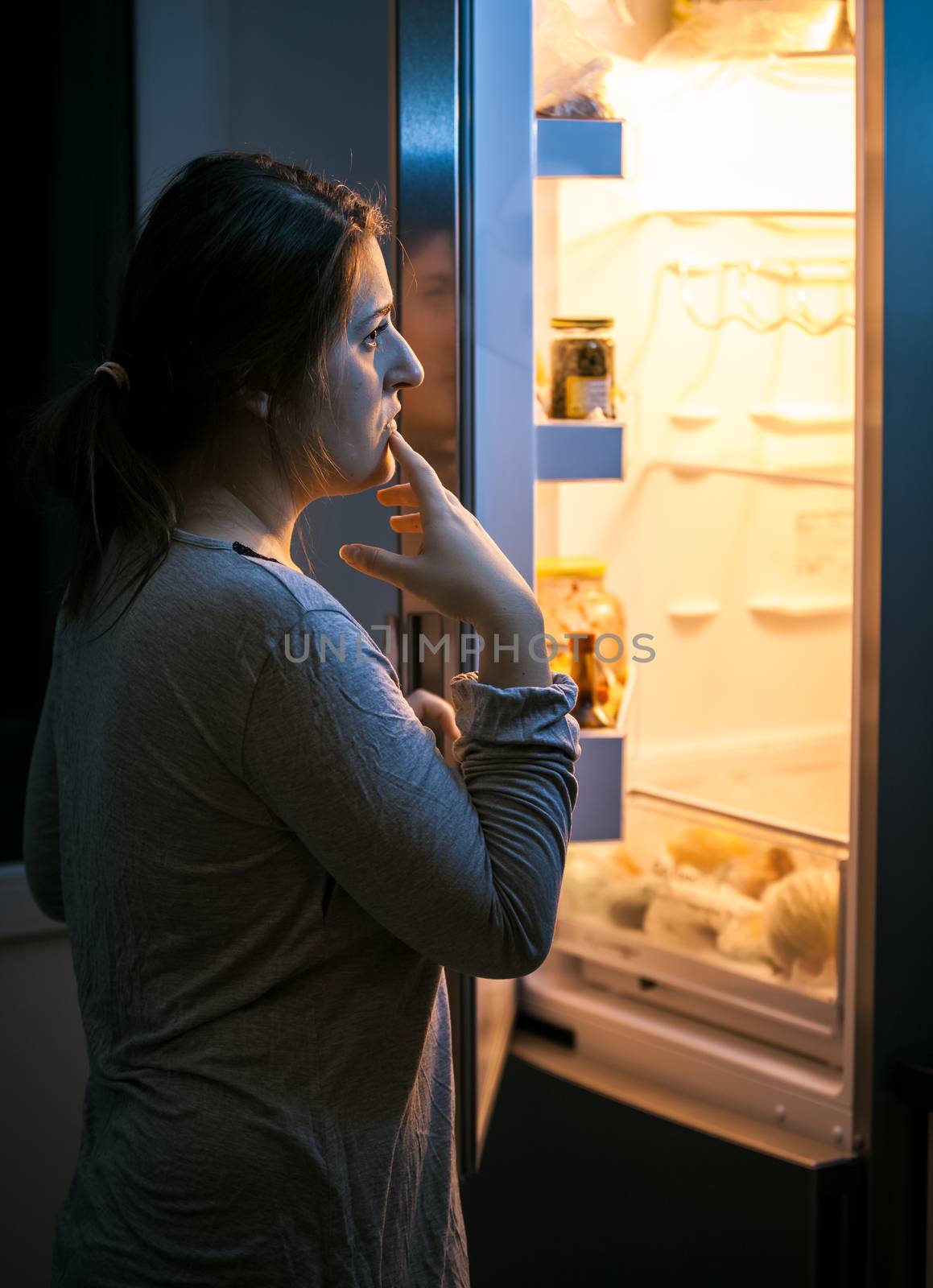 Young woman looking in the refrigerator at late evening
