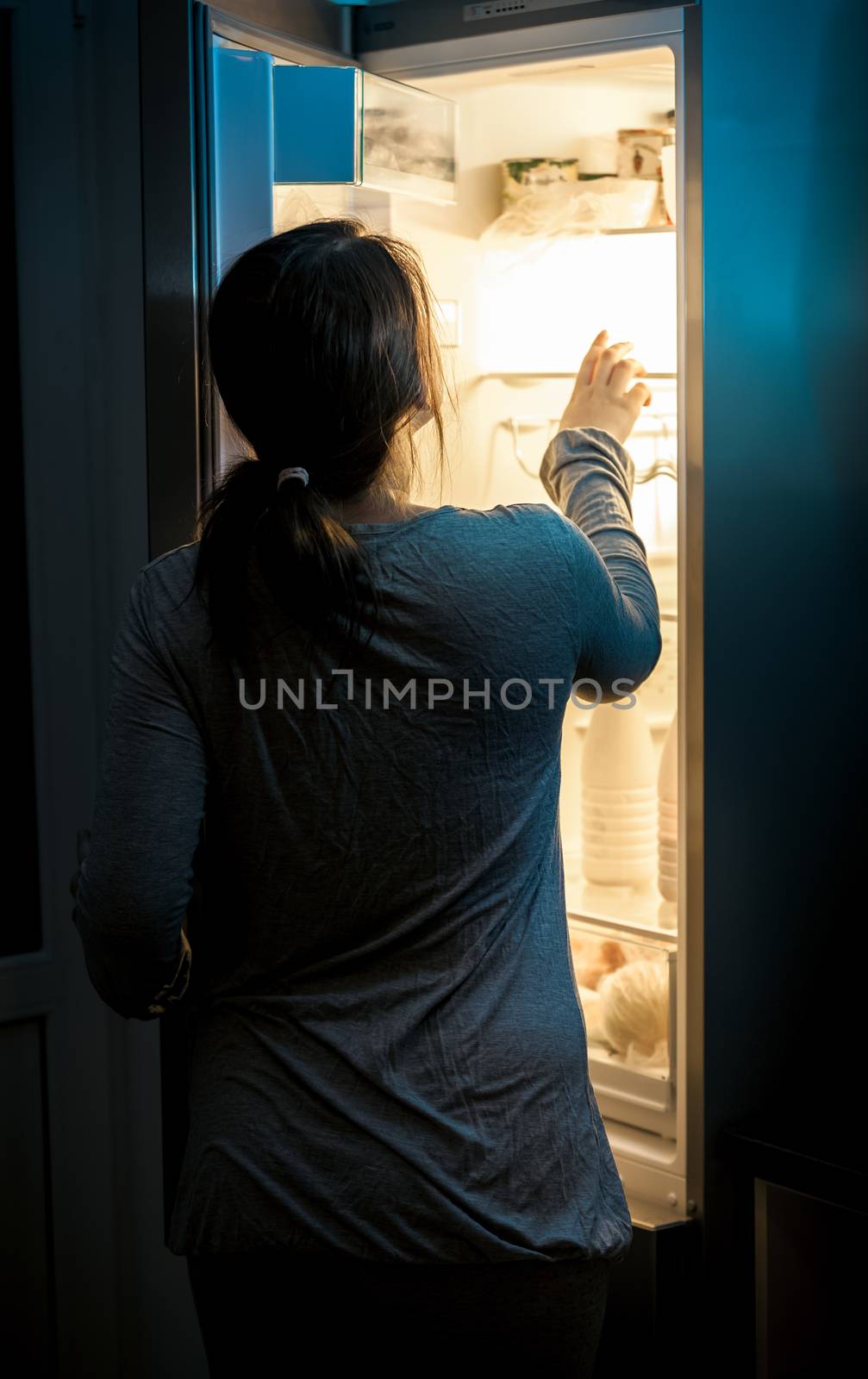 Portrait of hungry woman looking in fridge at late night