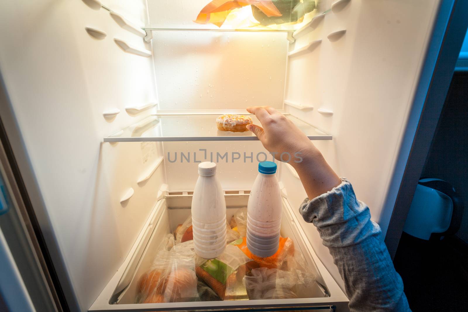 Closeup portrait of female hand taking donut from fridge