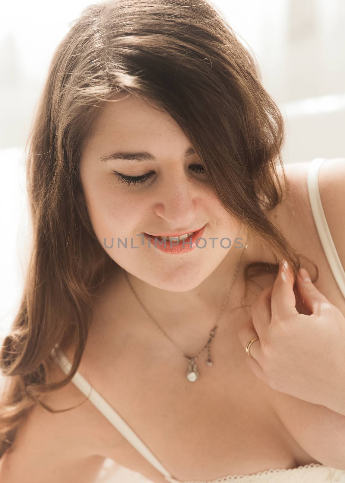 Brunette woman wearing necklace lying in bed