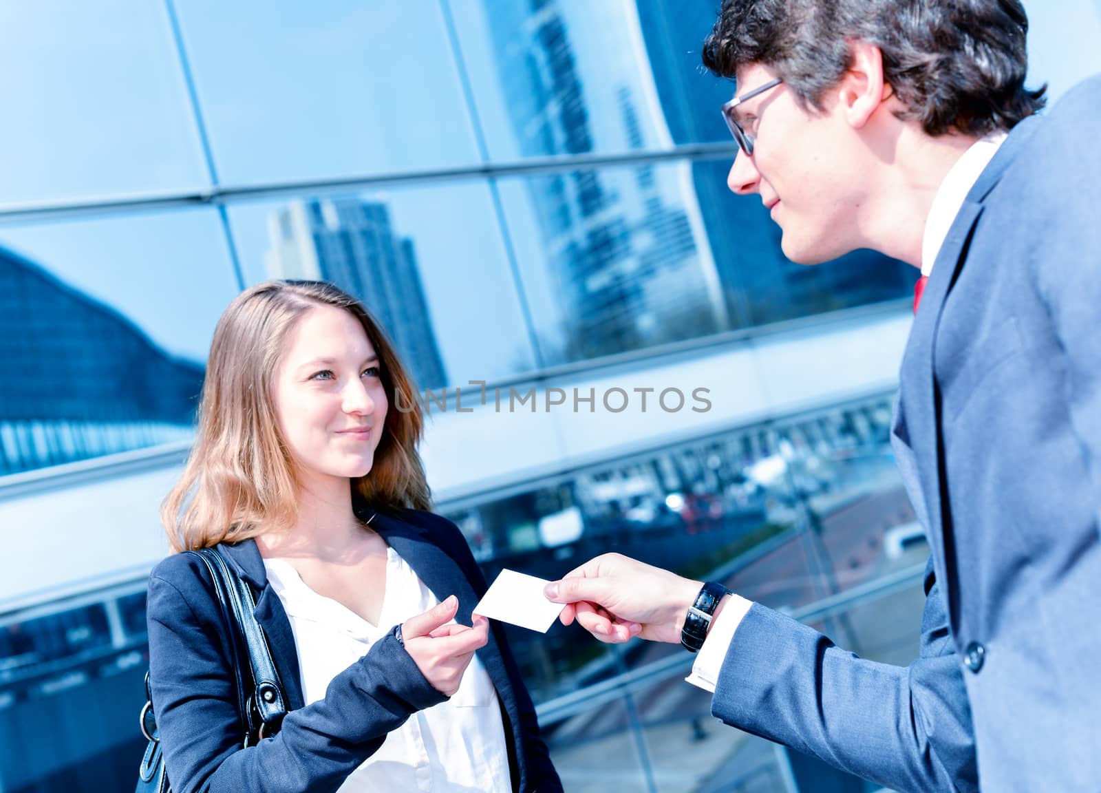 Junior executives dynamics exchange their business cards in front buildings