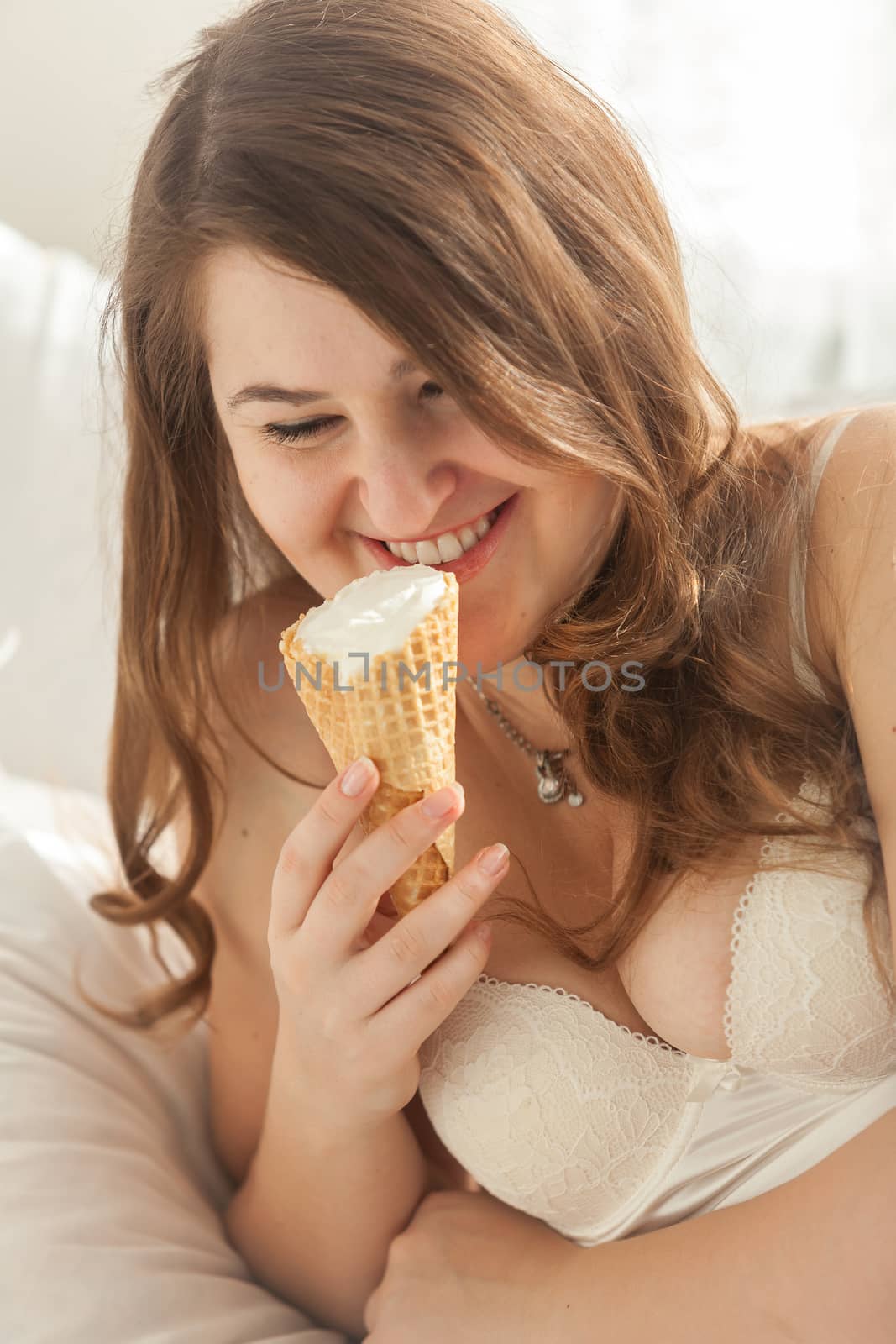 Portrait of sexy woman eating ice cream cone in bed