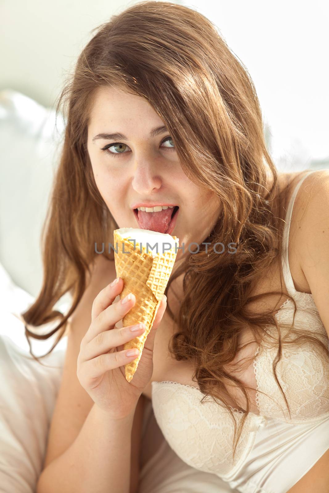 Lady in lingerie licking ice cream in bed by Kryzhov