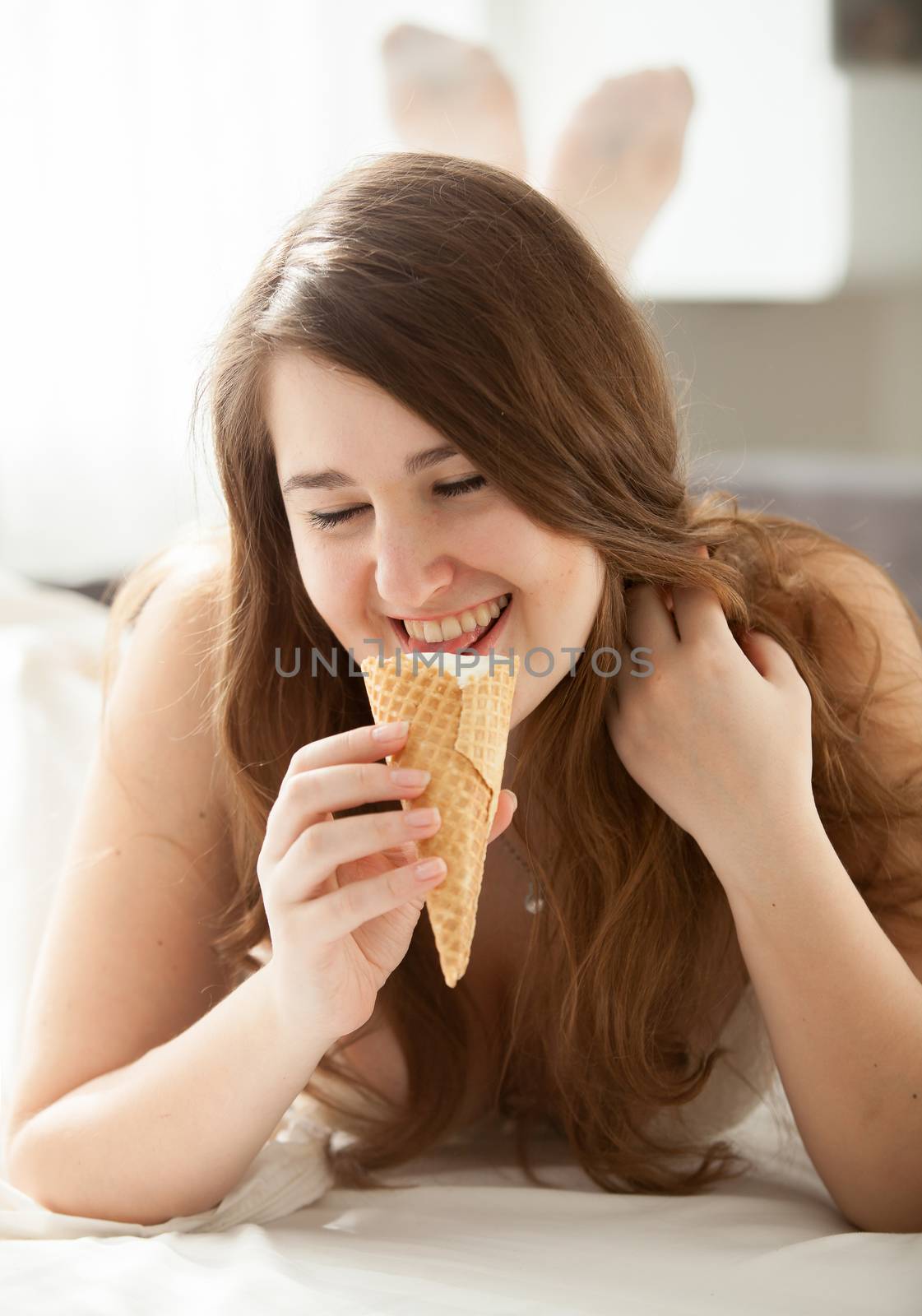 Brunette woman eating ice cream at bedroom