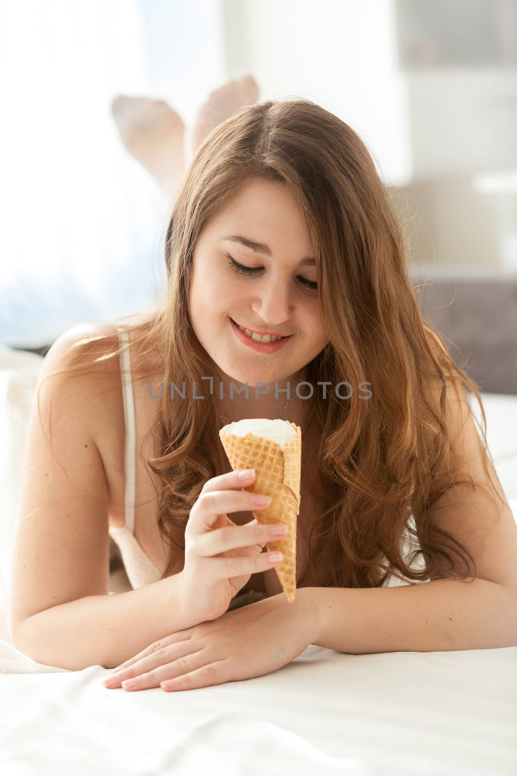 Girl lying on bed and looking at ice cream cone