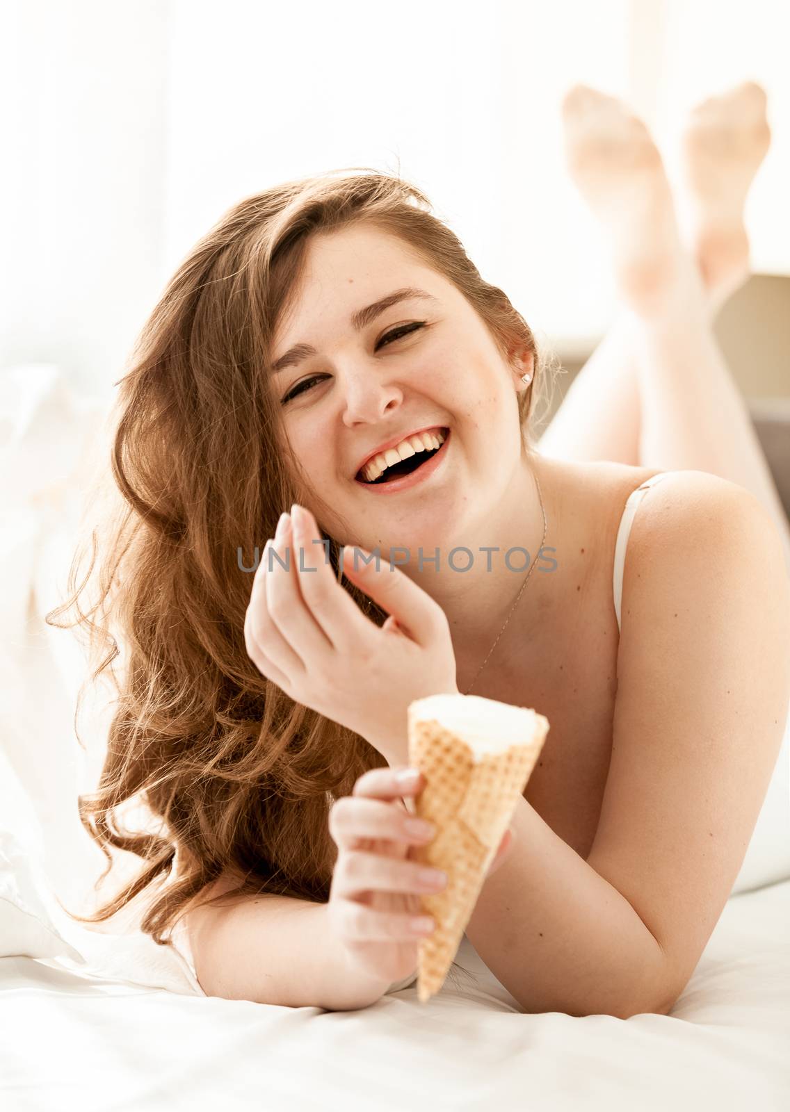 Portrait of sexy woman licking ice cream in bed