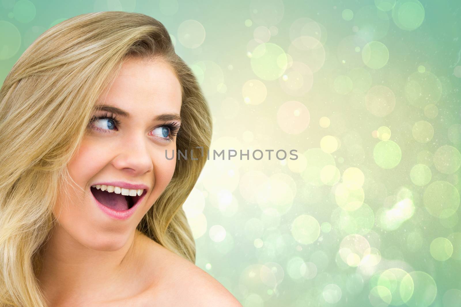 Smiling blonde natural beauty against green abstract light spot design