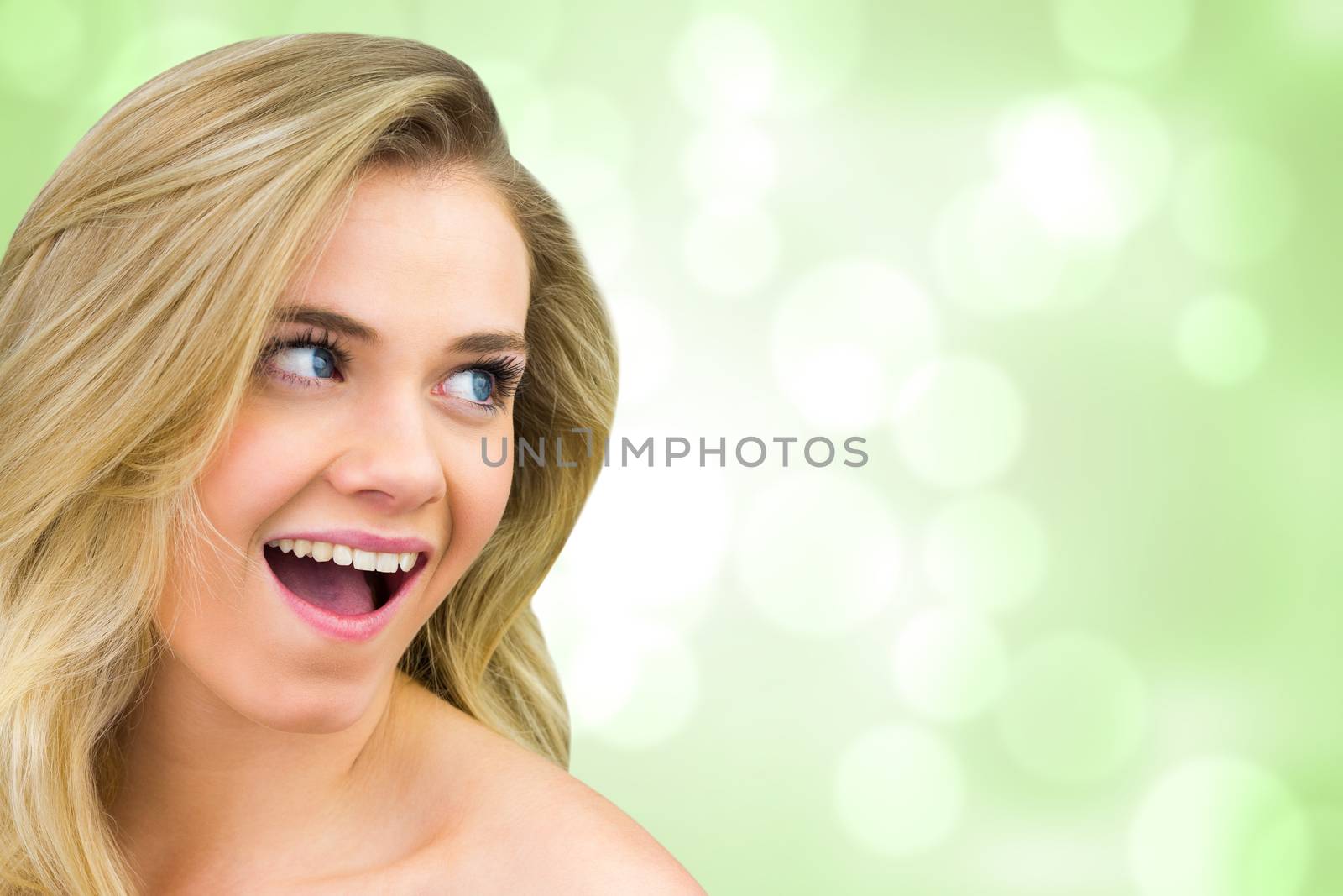 Smiling blonde natural beauty against green abstract light spot design